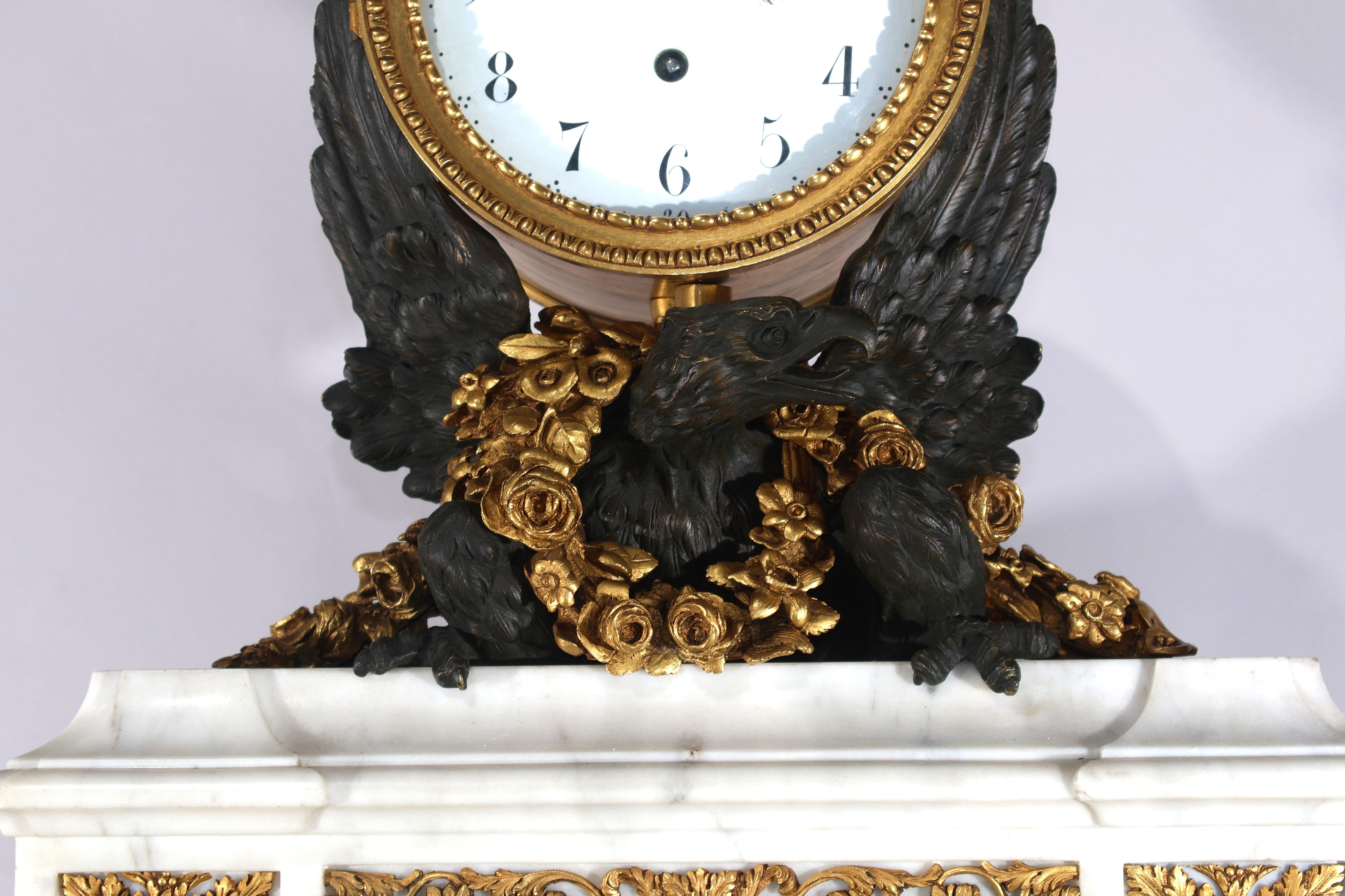 Magnifique horloge en marbre de Carrare, bronze patiné et bronze doré de style Louis XVI. Un travail de ciselage exquis. France, vers 1890. 
Dimensions : Hauteur 20