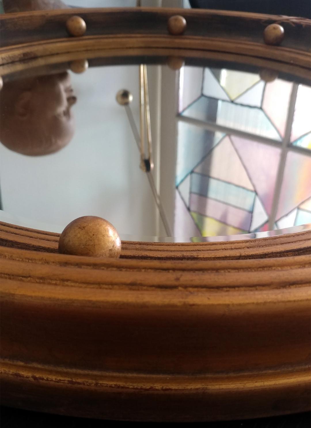 A lovely patinated gilt convex mirror in the Regency Style.
Having a concave frame set with gilded spherules within a circular beveled mirror.