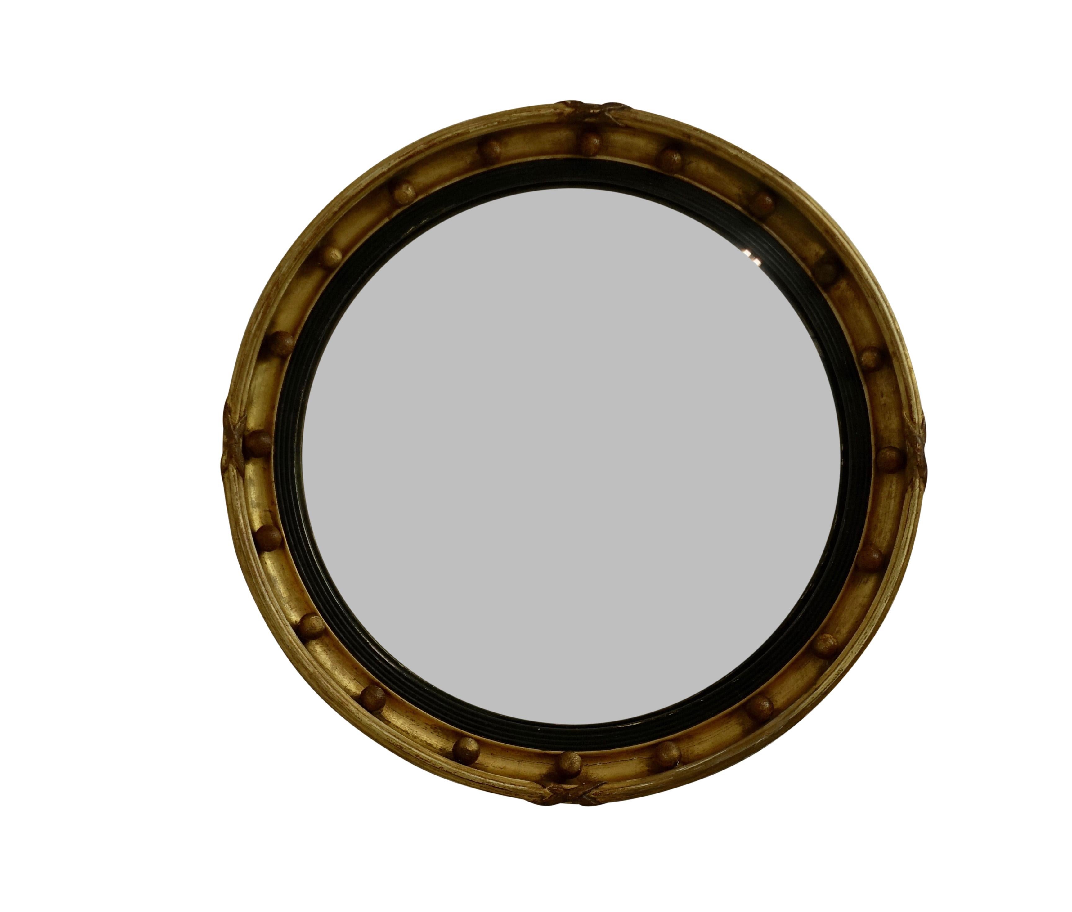 Antique Regency period gilt convex mirror with ebonized reeded inner molding and ribbon bound edge in original finish and original mirror with marring and scratches. English, circa 1840.