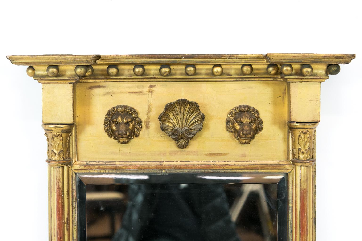Gilt Regency mirror, the cornice has balls, and the frieze has two lion masks with a scallop shell carved in high relief. The styles are sanded cluster columned and have an acanthus carved capital at the top. The mirror has a three quarter inch