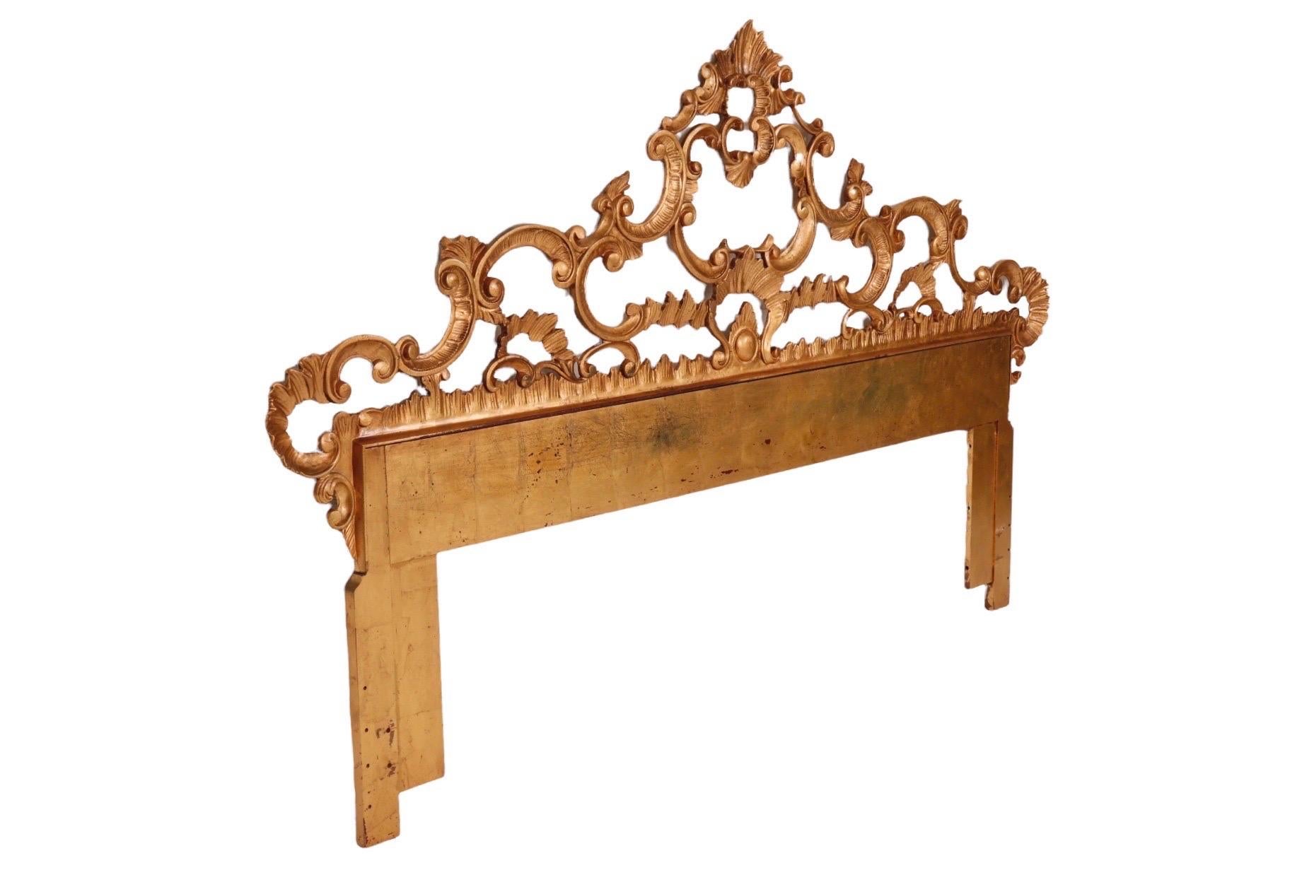 A gilt king size headboard made of metal, elegantly cast with fretwork in the French Rocaille style. Symmetrical scrolls & acanthus leaves undulate throughout with pebble and shell details.