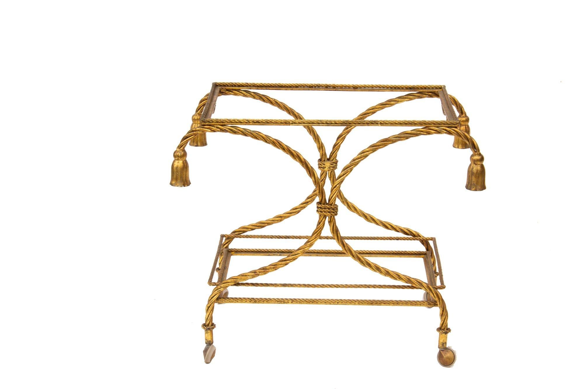 Italy, 1960s
Gilt Rope and Tassel Bar Cart. Classic Hollywood Regency style. High quality casters.
CONDITION NOTES: No glass. We can have glass cut to fit this or direct you on where to get it done. If shipping the item, it will be best to order