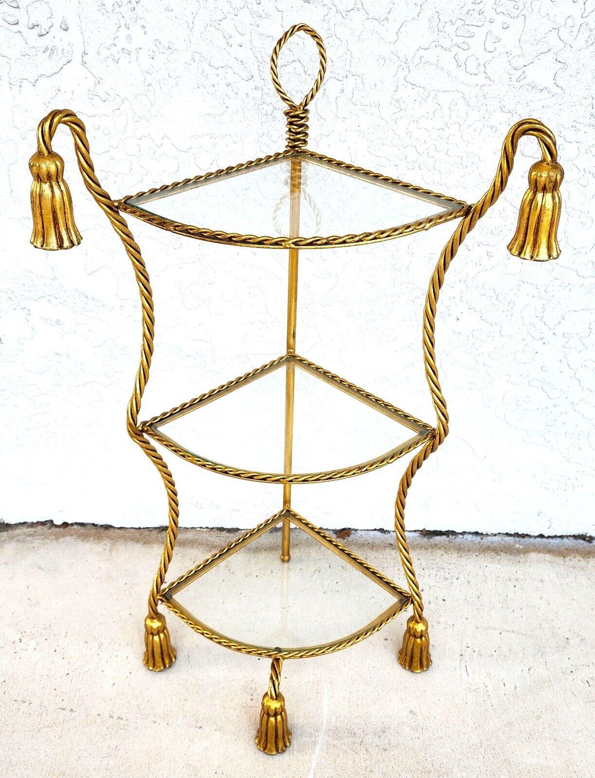 For FULL item description click on CONTINUE READING at the bottom of this page.

Offering One Of Our Recent Palm Beach Estate Fine Furniture Acquisitions Of A
Vintage Gilt Metal & Glass Corner Table Shelf Rope & Tassel
This can also be