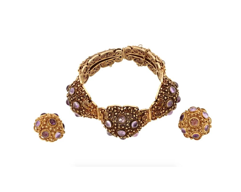 A vintage gilt sterling silver filigree jewelry set garnished with amethyst cabochons. The set includes a pair of clip-on earrings and a hinged bangle bracelet. Hallmark Silver is on the bracelet clasp. Total Weight: 56 grams. Vintage Elegant