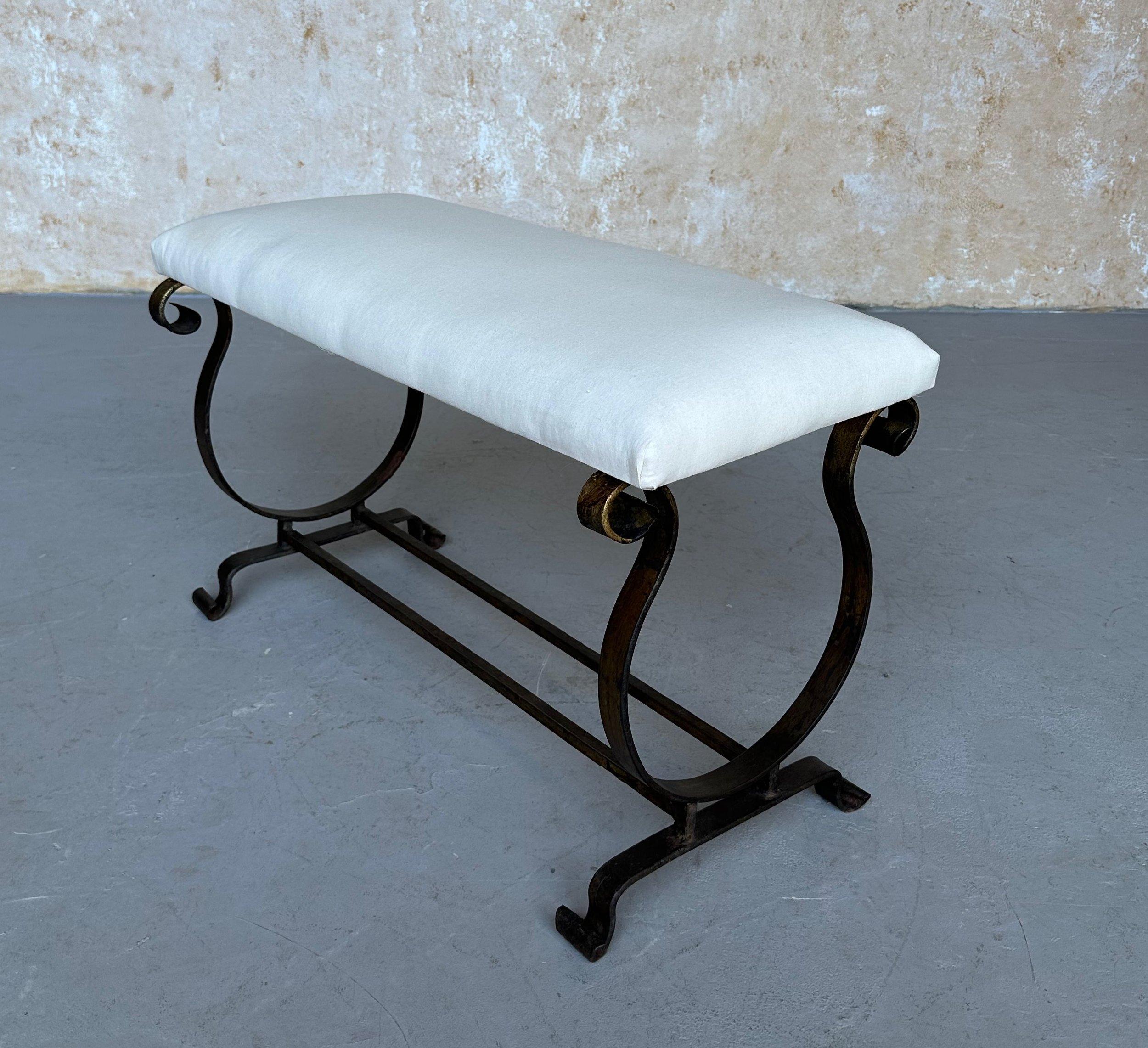Banc en fer espagnol vintage des années 1950, dont la base en forme de lyre et la patine dorée foncée appliquée à la main témoignent d'un savoir-faire exceptionnel. Le design se caractérise par un double châssis, des pieds qui s'enroulent vers le