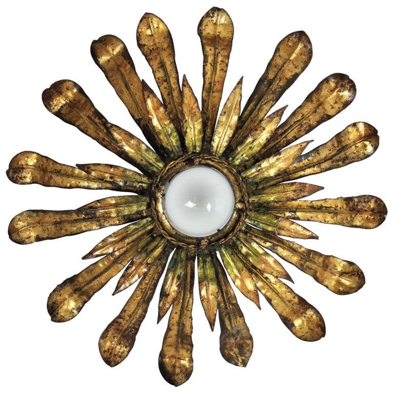 Gilt metal sunburst flower flush mount light fixtgure with green accents, 1950s
Eye-catching hand-hammered iron floral sunburst light fixture with gold leaf gilding and green accents.
Terrific aged patina in gold leaf, green and rusty