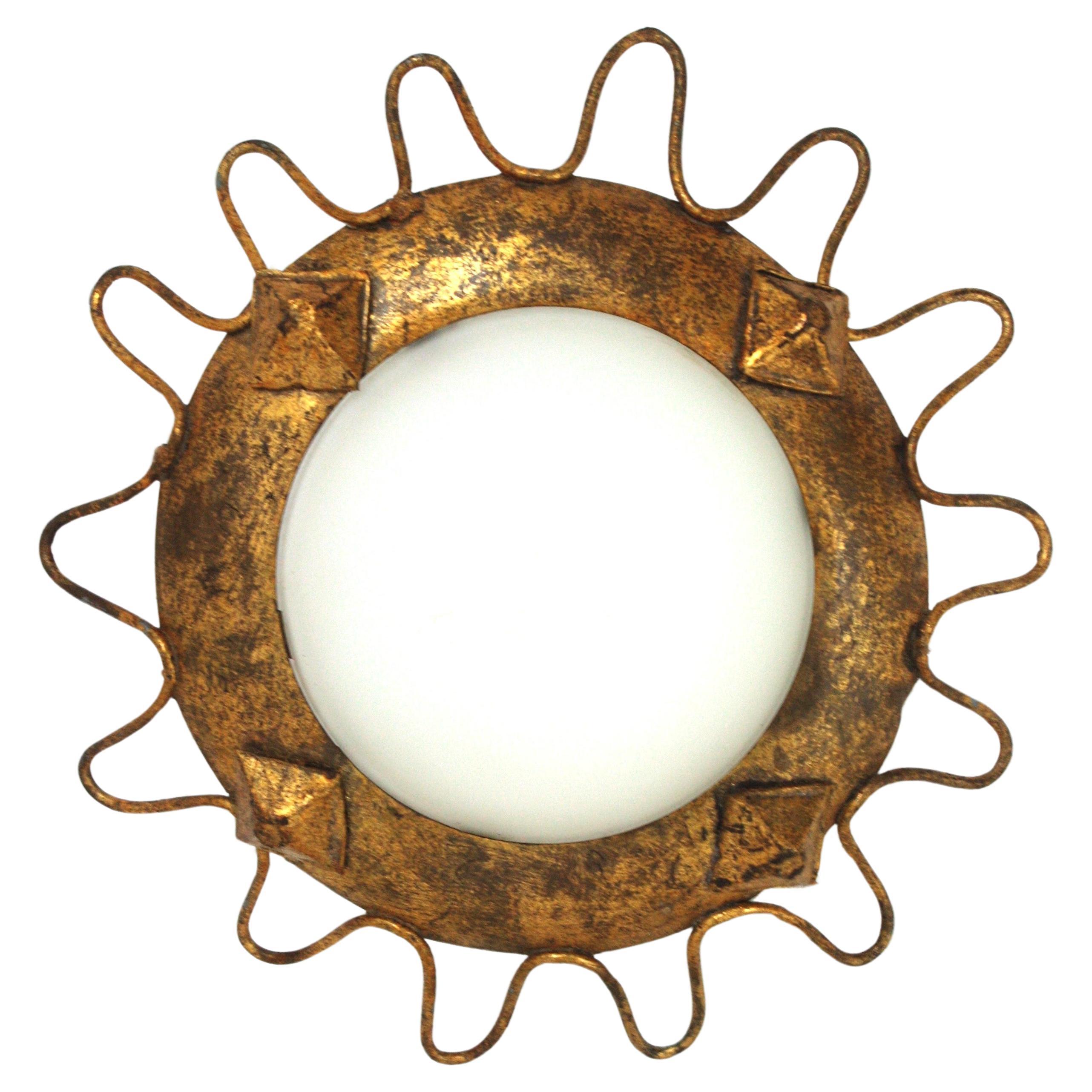 Wavy sunburst flush mount in Gilt Iron and milk glass. France, 1950s
Manufactured at the Mid-Century Modern period this light fixture has accents of Brutalist style. It has a looped edge, rhombus decorations on the frame and gold leaf finish.