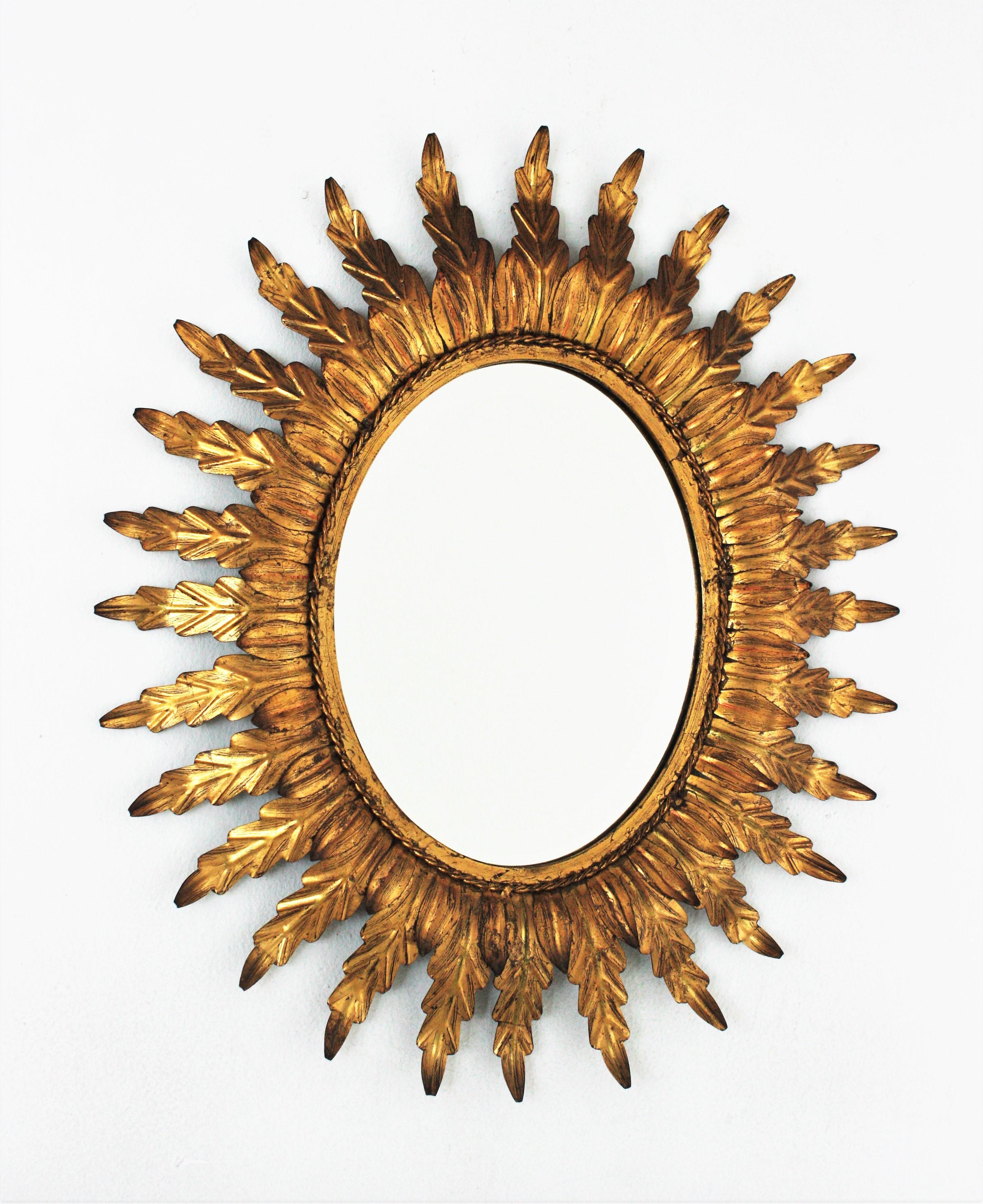 Oval leafed sunburst mirror, gilt iron, gold leaf. France, 1960s.
Hollywood Regency sunburst oval mirror in gilt metal with double leafed frame. The frame is comprised by a layer of small leaves and a twisted iron rope surrounding the glass and