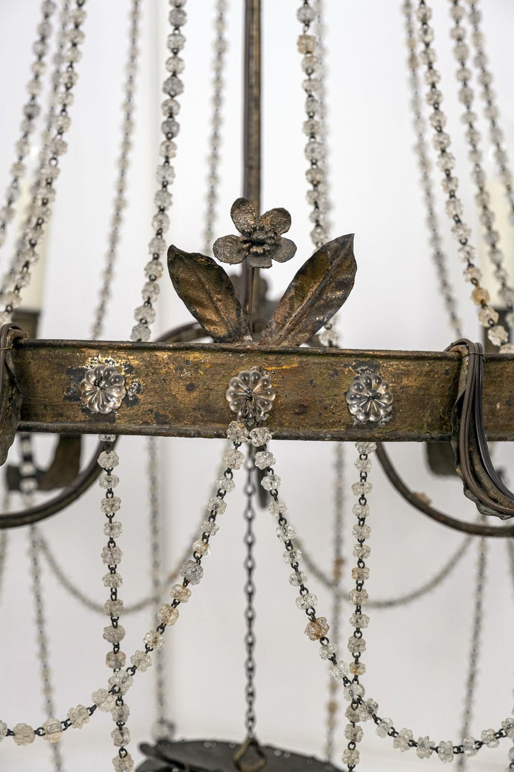 Gilt tole and glass French Empire: Neoclassical style chandelier constructed circa 1820-1850 from gilded tole and iron. Decorated in chains of glass beads, pressed glass flowers and a Murano hand blown glass prism. Newly wired for use within the USA