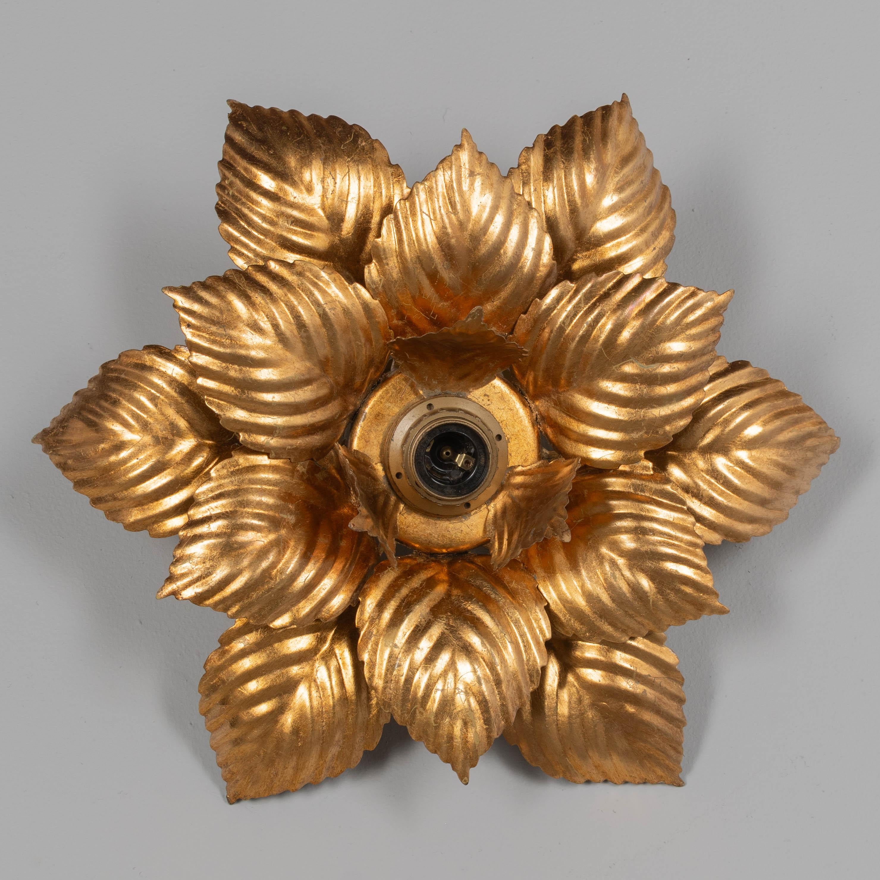 A Mid-Century Modern Italian gilt metal flush mount ceiling fixture or wall light designed by Masca, a company based in Florence. Lotus flower shape with three layers of 24 karat gold leaf tôle petals, or leaves. Beautiful effect when illuminated.