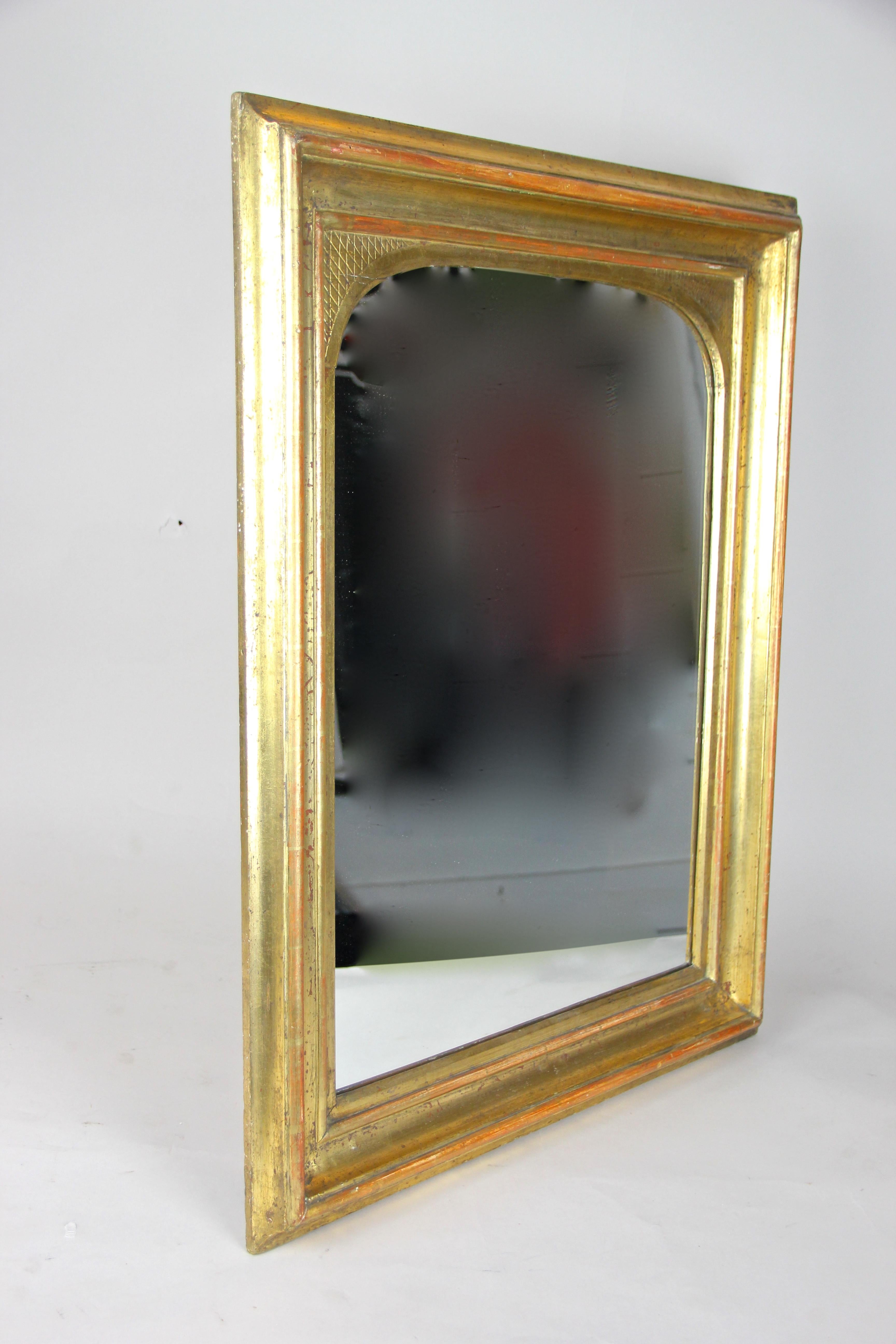 Remarkable gilt wall mirror from the early Biedermeier period in Austria, circa 1825. In an absolute fantastic original condition, no former restorations (we just had to renew the mirror glass) and covered with fine gold leaf on red Bolus which you