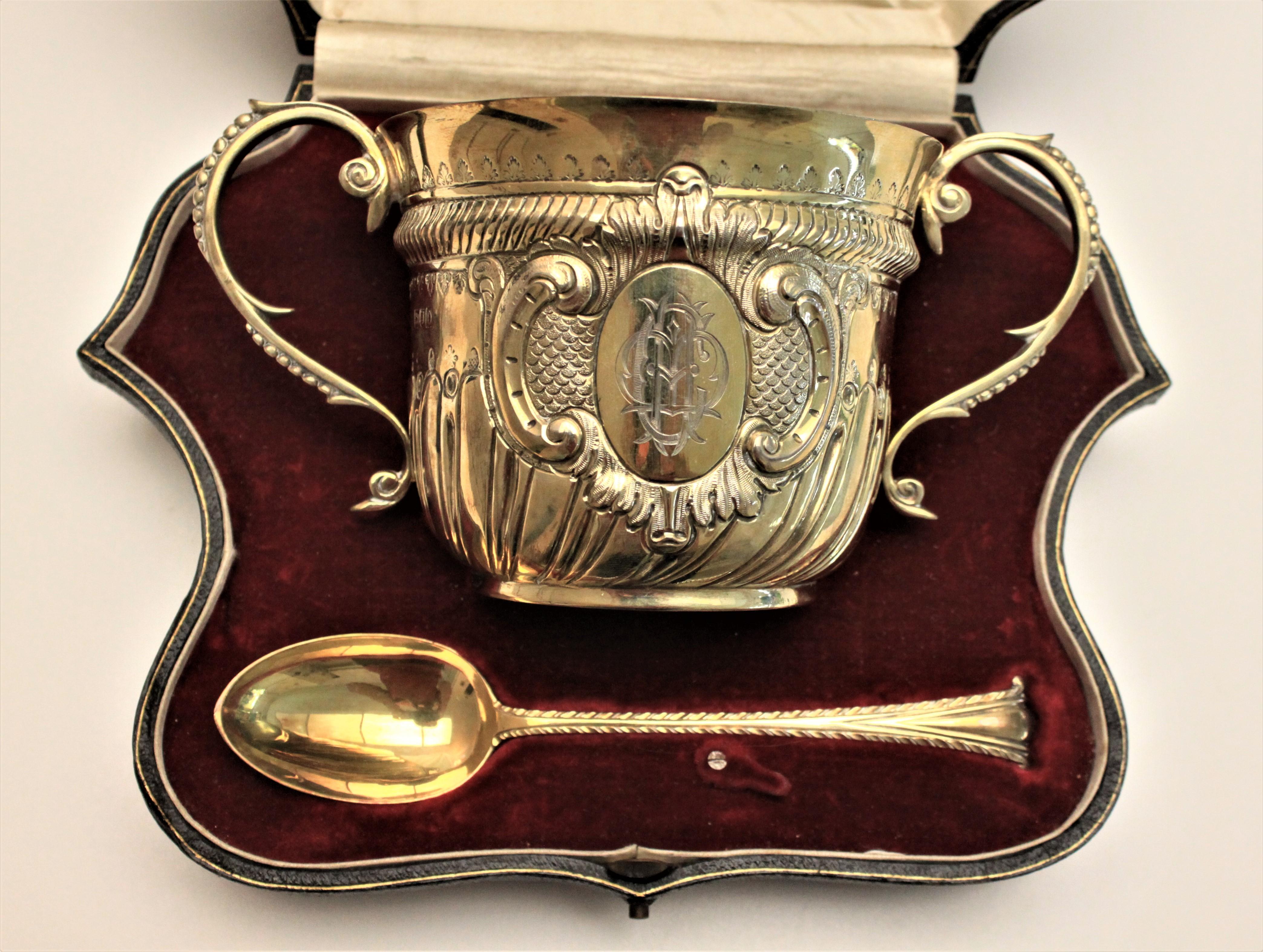 This sterling silver loving cup and spoon were made in England in the Victorian period and style. The cup is ornately decorated with repousse and chased work and has beaded handles and a heavy gilt washed interior and a lighter gilt finish to