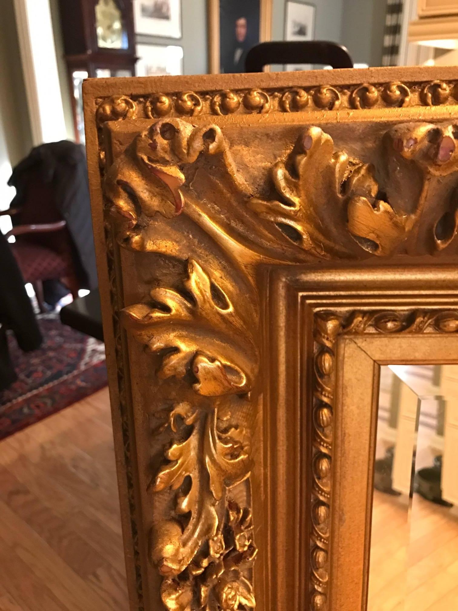 Carved wood and gesso beveled mirror with a thick and detailed frame. The frame is layered with scrolling figures, acanthus leaves and borders. This mirror can be hung horizontally or vertically. Elegant old world styling in great well cared for