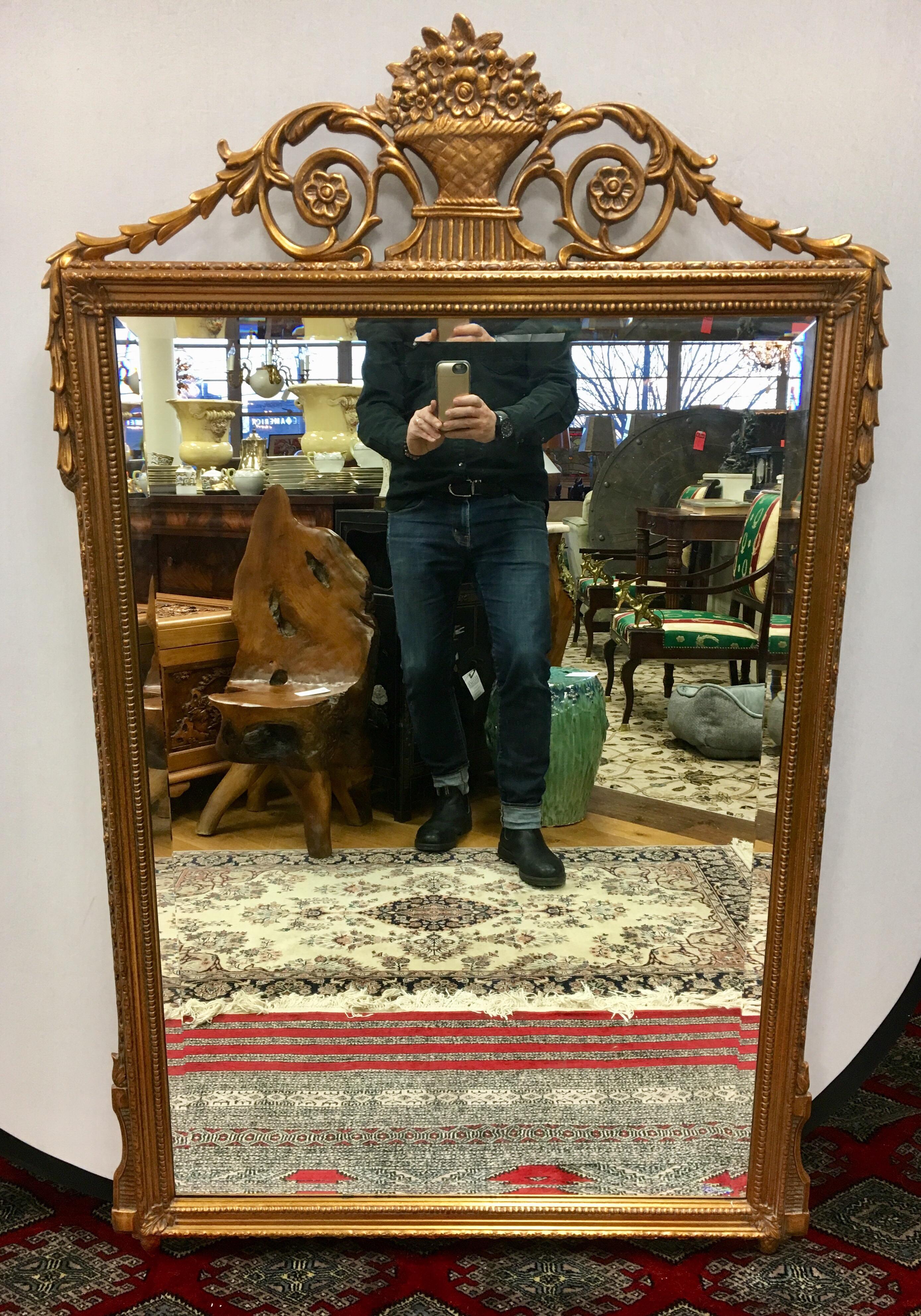 Intricately carved gilt mirror with Horn of plenty medallion at top and carved wreaths descending from top. Mirror is beveled and in perfect shape.