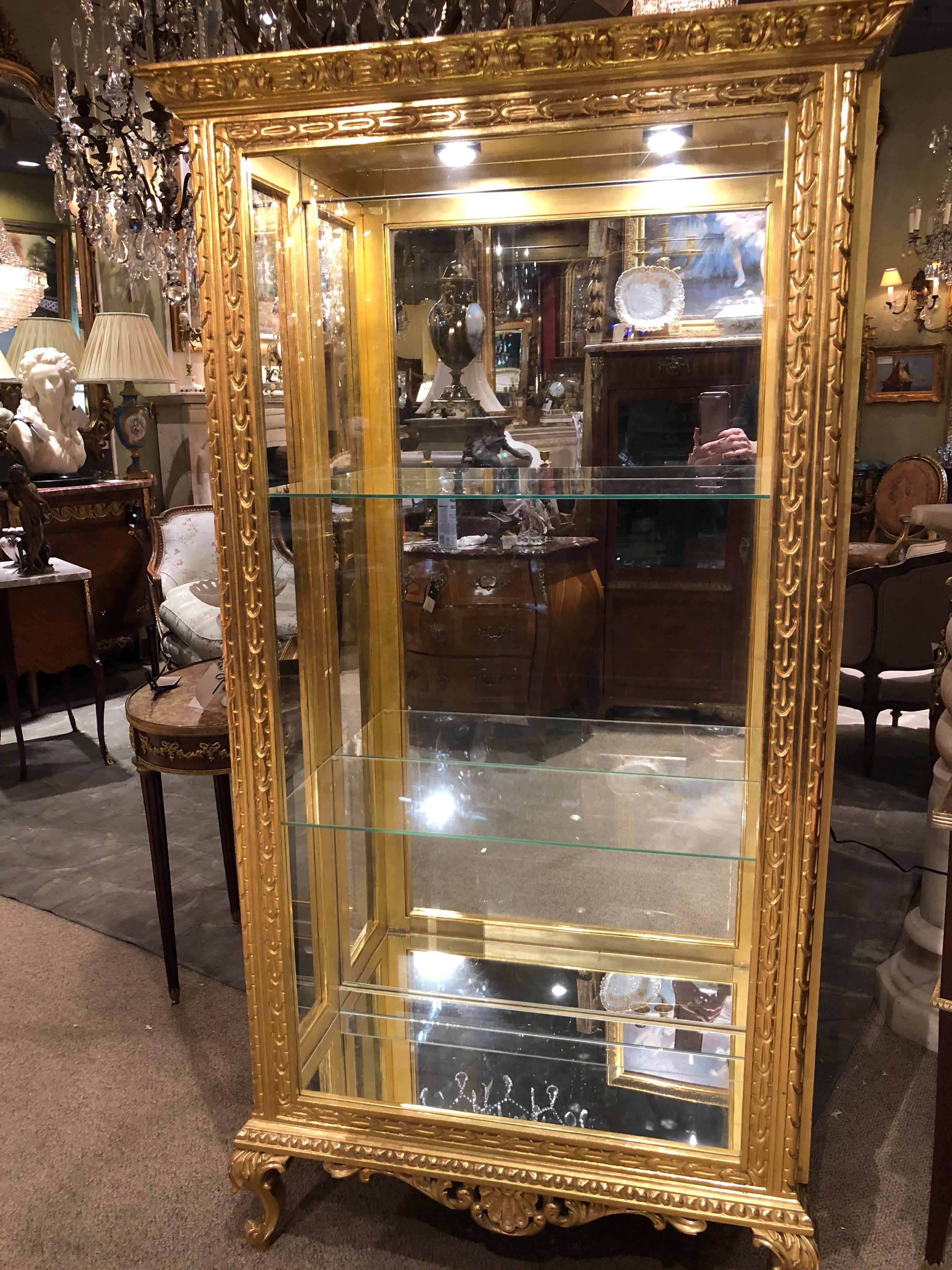 Mirror back with lighting and two glass shelves
Side opens on both sides which leaves the
Front very clear for display. The gilding is
Original.