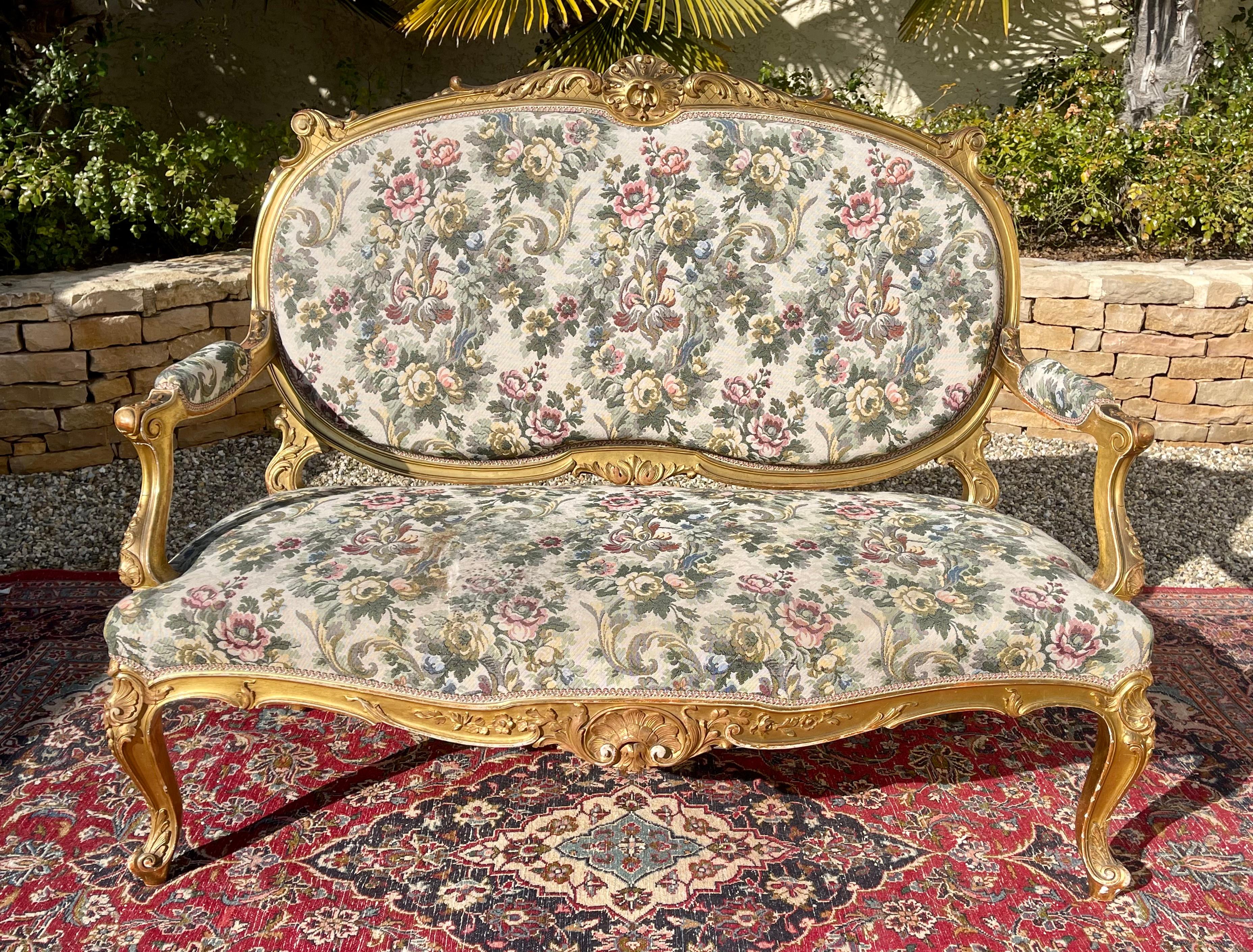 Superb living room in gilded wood in Louis XV style composed of 7 pieces: sofa, 2 armchairs and 4 chairs. The whole is covered with a floral tapestry. 2 chairs are upholstered with a different fabric. Very nice model in good