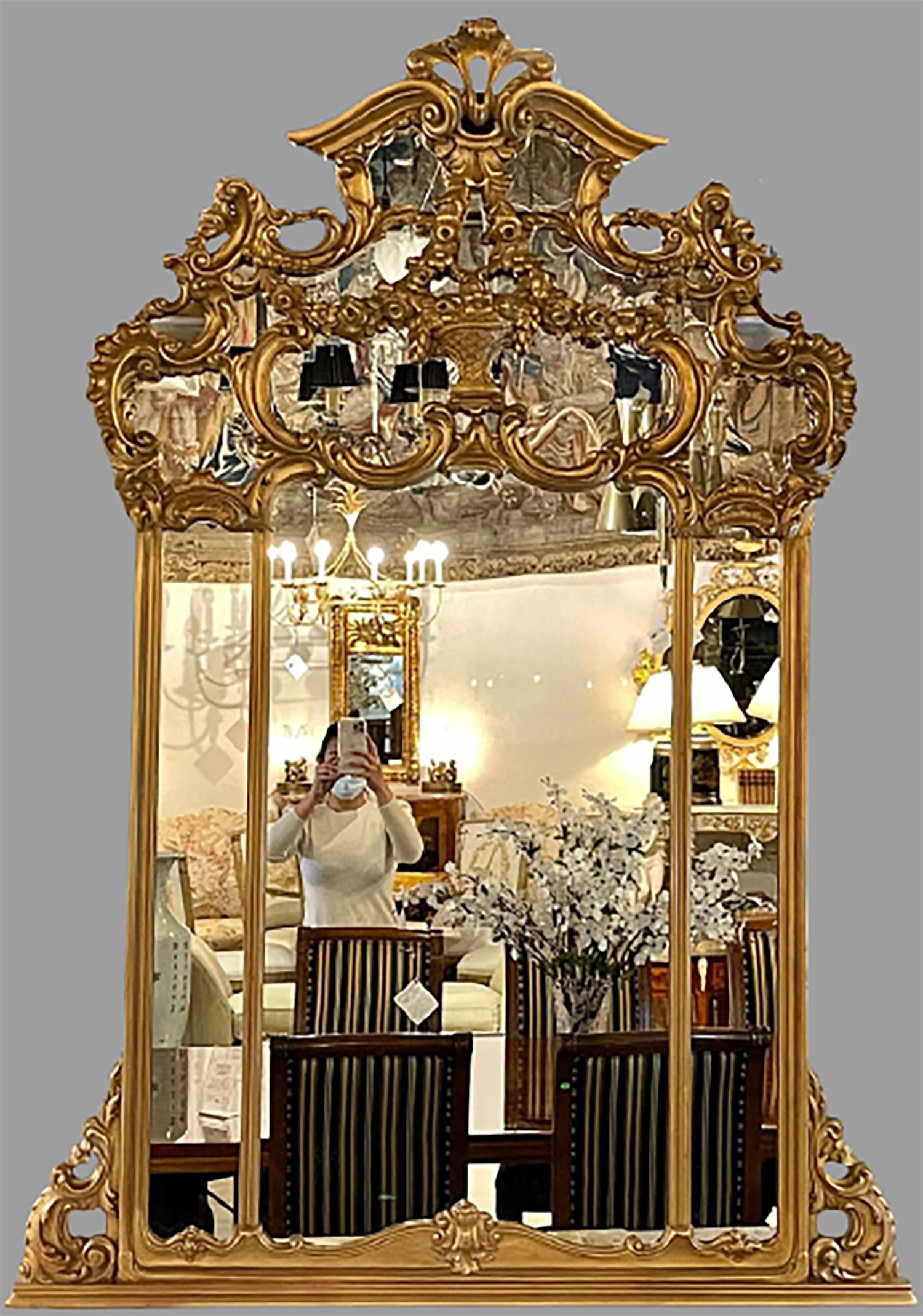 Giltwood over the mantel mirror. This wall or console mirror is simply stunning and certain to add a fine reflection to any home setting. The clear center mirror flanked in a carved gilt frame of Louis XVI fashion and design having a central theme