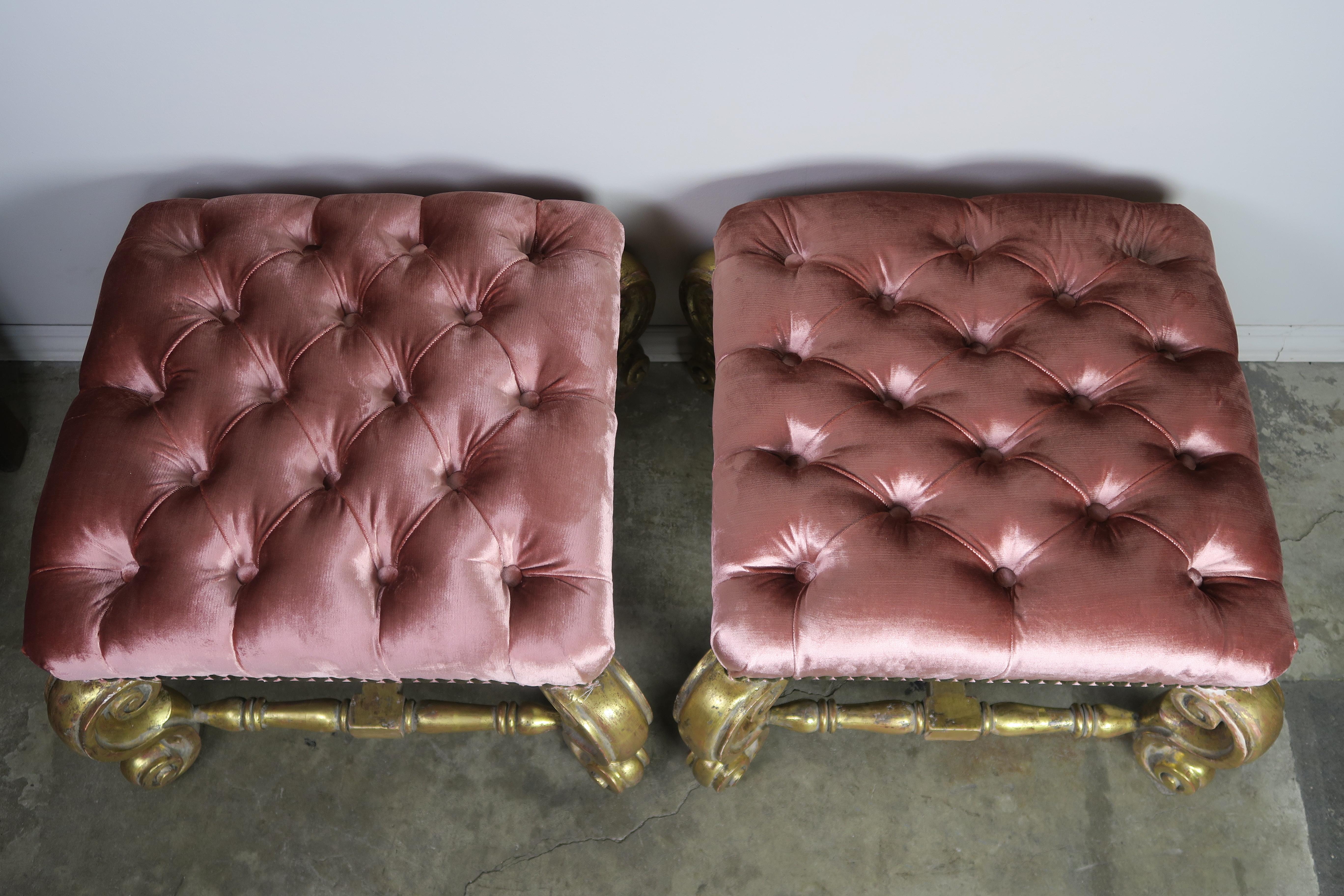 Pair of French style giltwood benches standing on four cabriole shaped legs that are connected by a bottom stretcher. The benches are upholstered in a beautiful pink tufted velvet and detailed with custom nailhead trim.