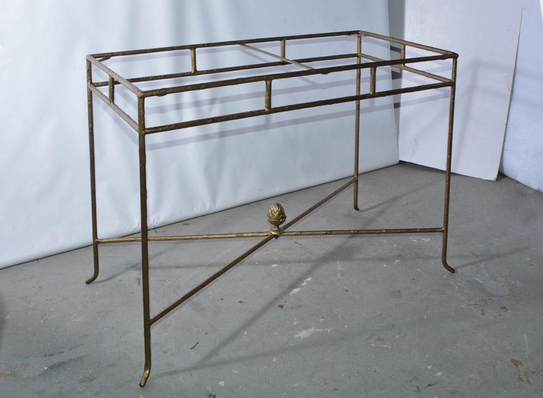 The contemporary metal console table has a gilt wrought iron structure with a branch-like texture and a frosted glass top inset into a frame and held in place by a center and corner braces. A stylized acorn embellished the crisscross braces.