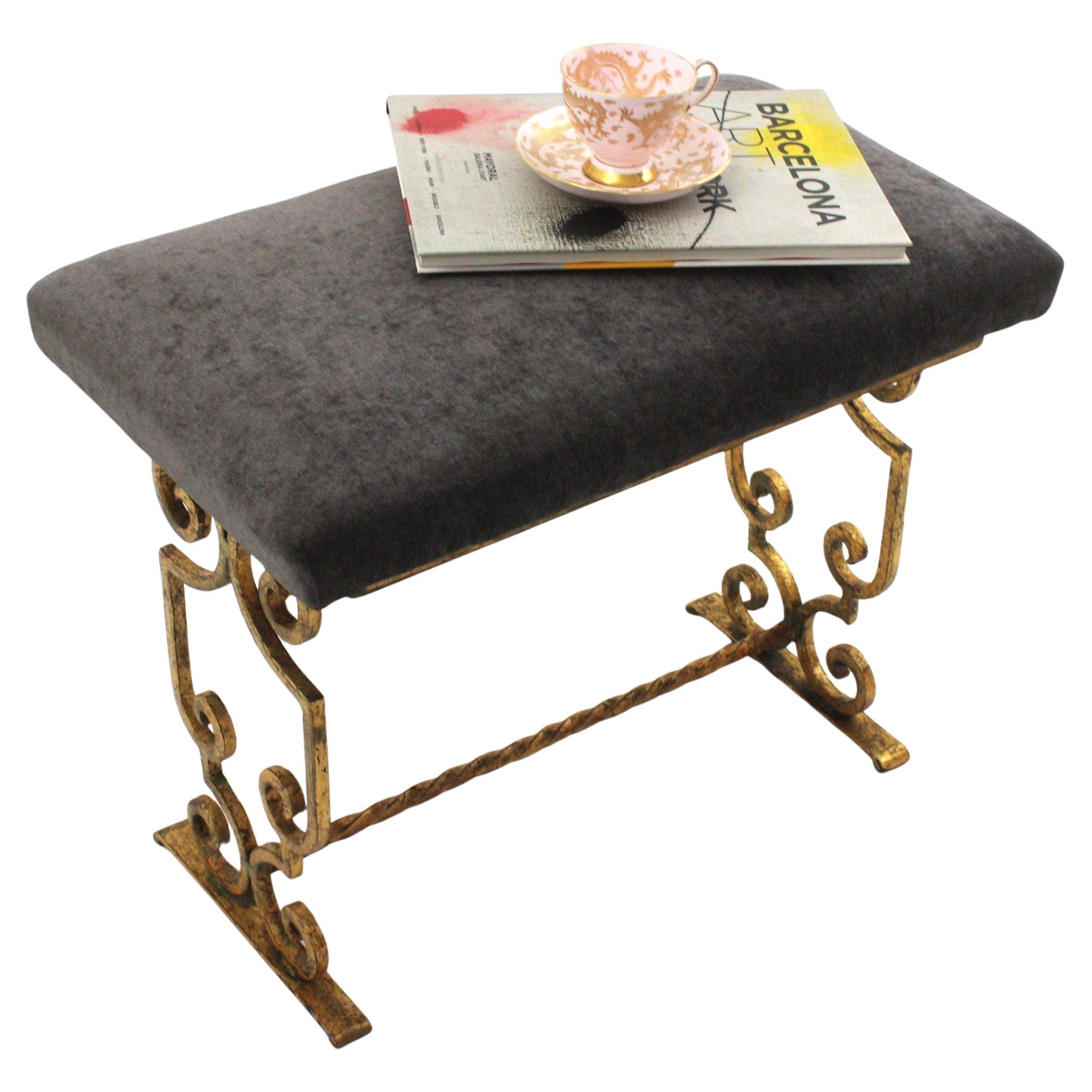 French Gilt Iron Bench with Scrollwork details and grey velvet, 1940s
In the manner of Gilbert Poillerat.
This upholstered bench stands on a hand forged iron base with scroll details and neoclassical inspiration.
Original patina and gold leaf