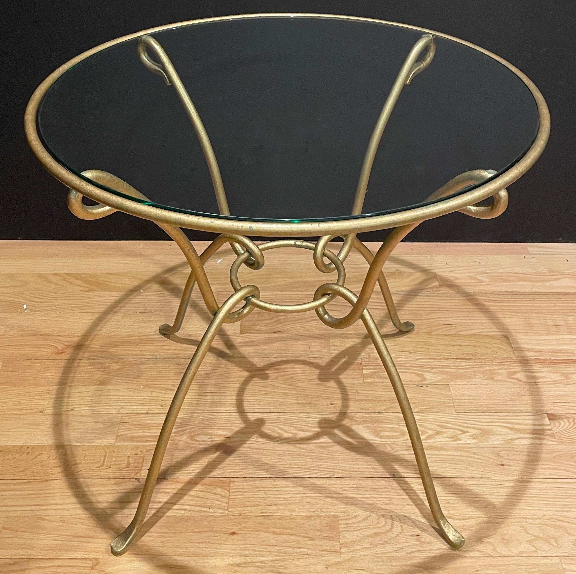 Minimal simplistic lines with an Art Nouveau feel, this Modern hand wrought iron, gilt finish table, can be used as an end table or center table. Glass top completes a light and elegant look.