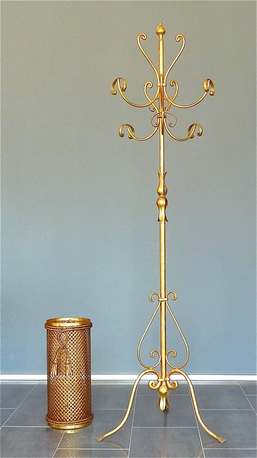 A beautiful Italian Midcentury gilt wrought iron and metal coat stand or hat rack in the style of Hans Kögl, Italy, circa 1950s. The coat stand which has a width of about 56 cm / 22.05 inches and which is 185 cm / 72.83 inches tall has a tripod