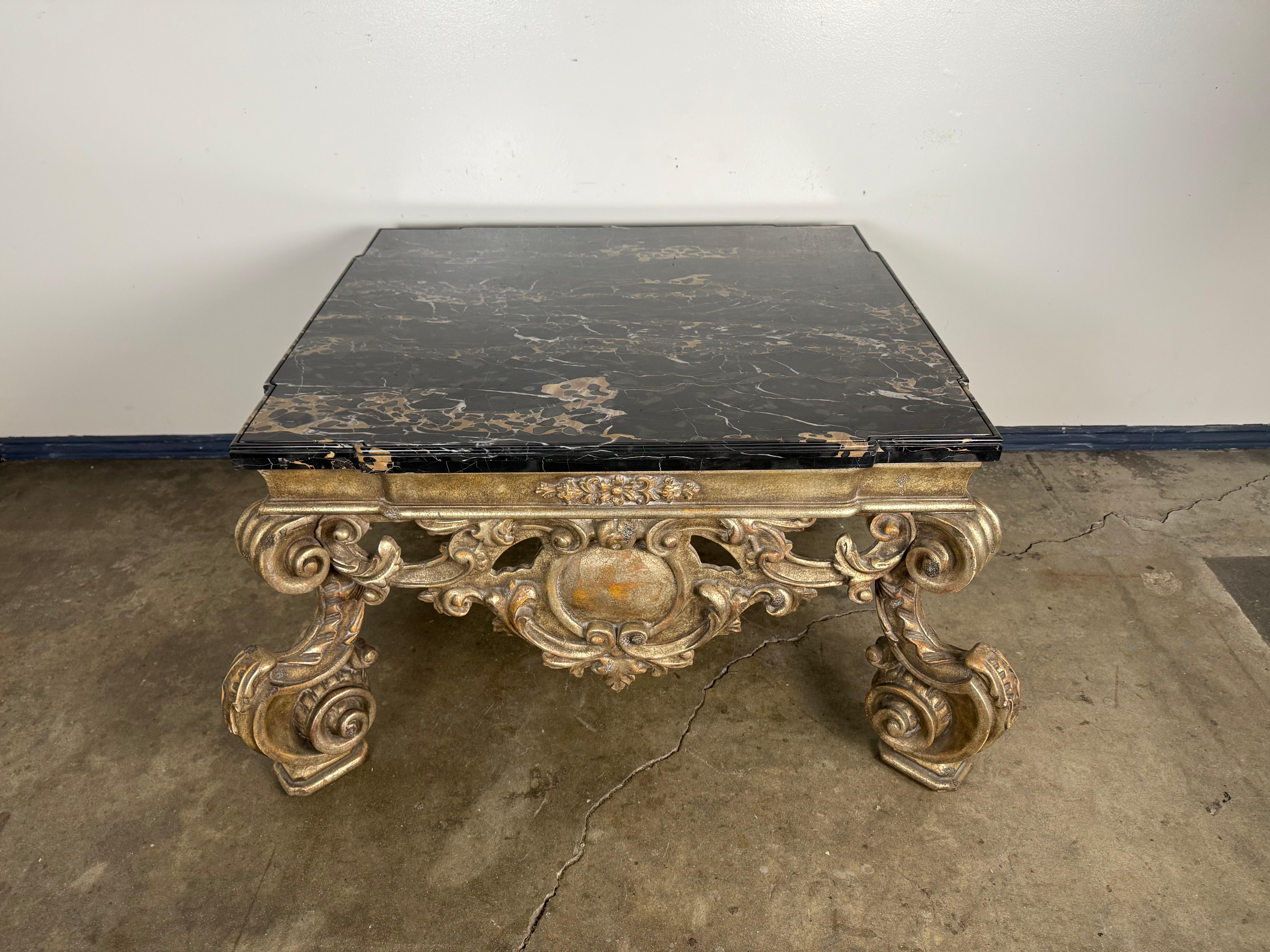 A highly sculptural Baroque Revival coffee table by Brustlin Workshop of Los Angeles, renowned for their fine artisan craftsmanship in the mid-20th century. The table features an elaborately carved giltwood base with scrolling acanthus motifs and a