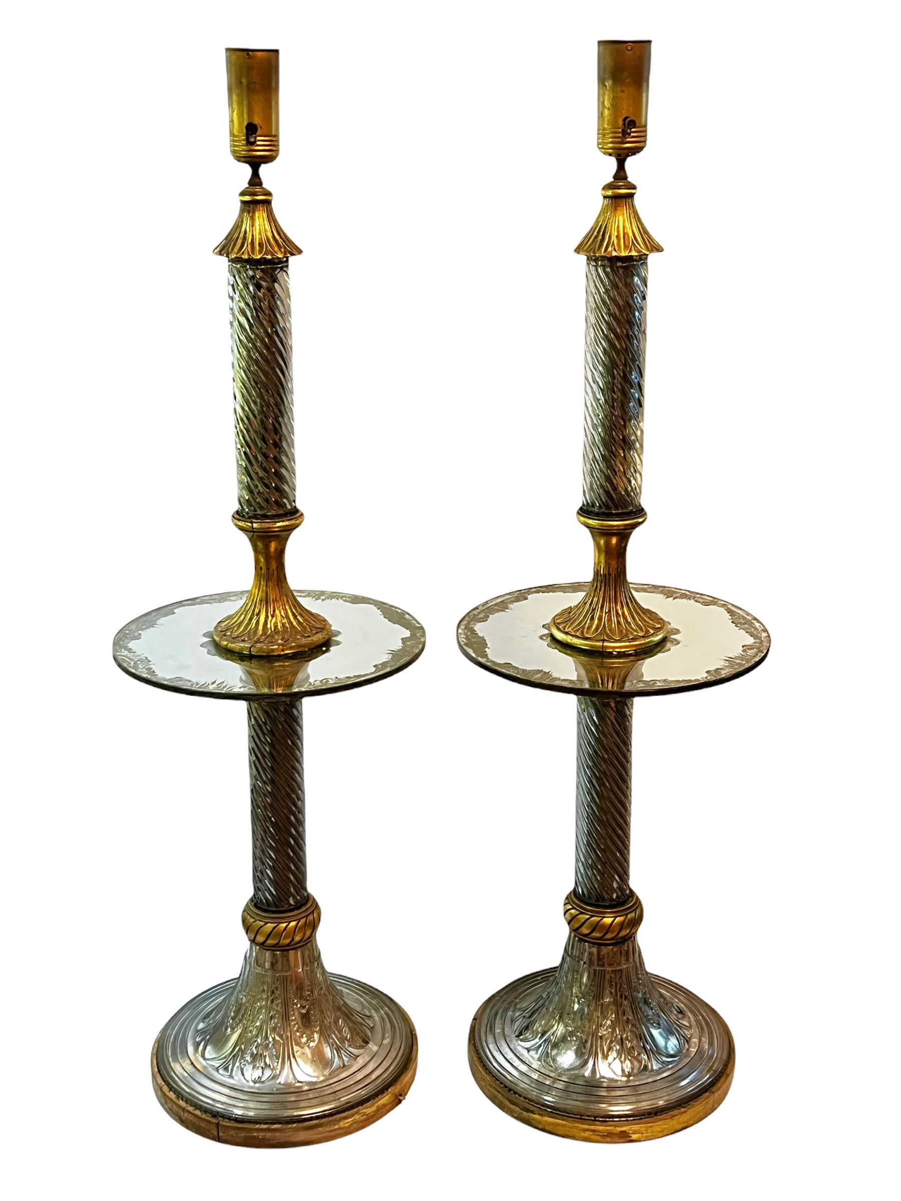 Our very rare pair of torchieres, attributed to Maison Bagues, feature standards of blown glass and carved giltwood, with round gilded glass table tops and reverse silvered glass pedestals, and their original sockets with ceramic diffusers.

In