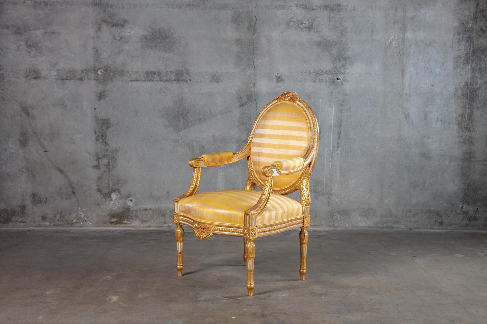 Pair of giltwood armchairs in upholstered in yellow striped fabric.