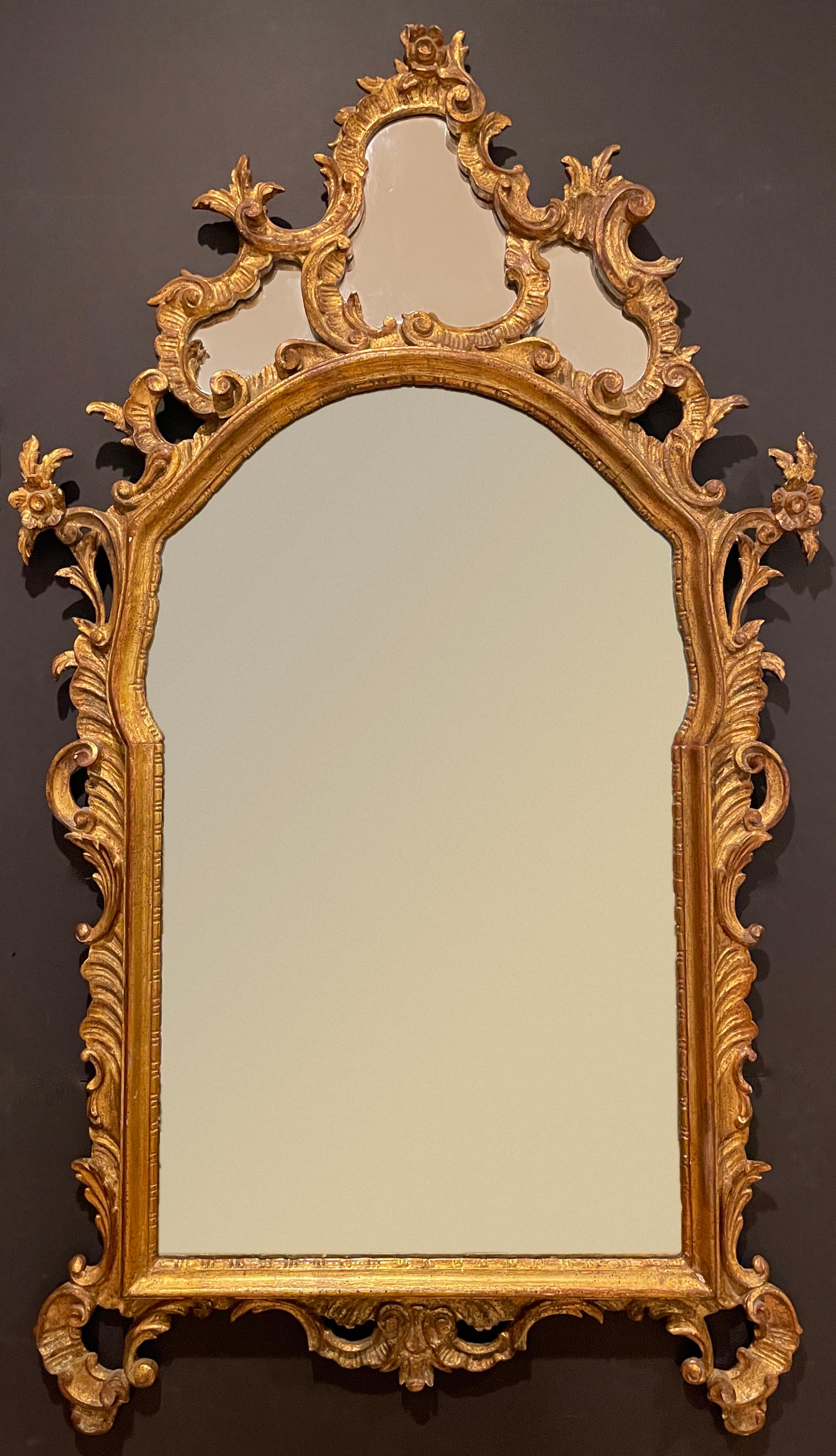 Finely carved giltwood Baroque style mirror with main mirrored panel and three mirrored panels at crest. Carved with scrolls and florals in the Baroque styling.