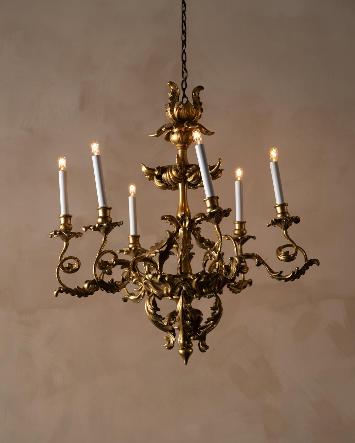 Lampadario a sei bracci in legno dorato che conserva la doratura originale. L'intaglio è superbo ed è nello stile del periodo barocco, con elementi di fogliame stilizzati. Non elettrificato. Condizioni coerenti con l'età.
