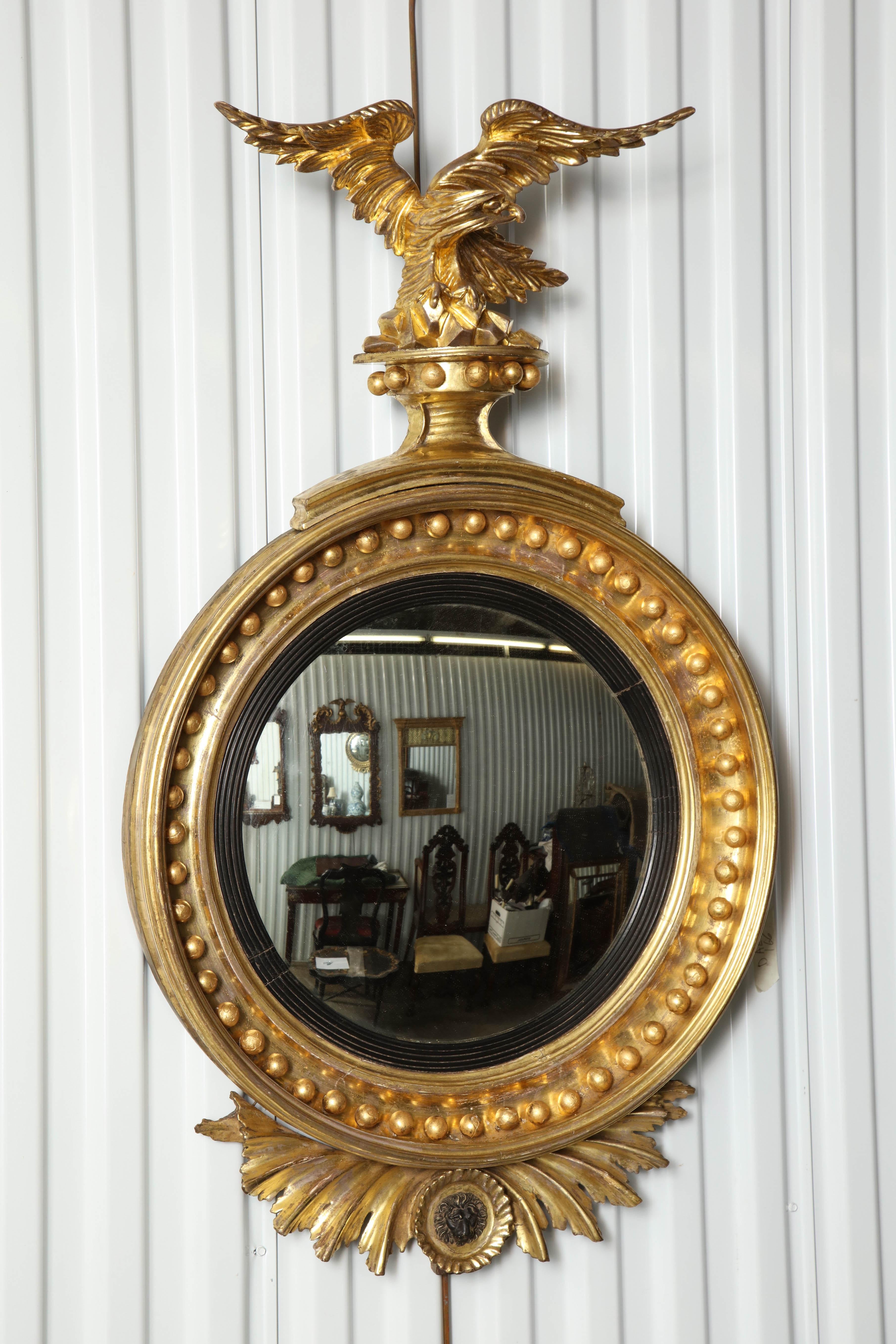 Giltwood convex mirror with eagle surmounts, reeded inner frame and numerous spheres.