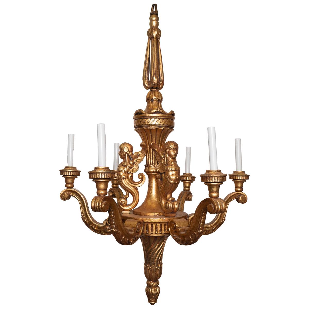 6-arm giltwood chandelier featuring ornate carved figurehead and foliate details.