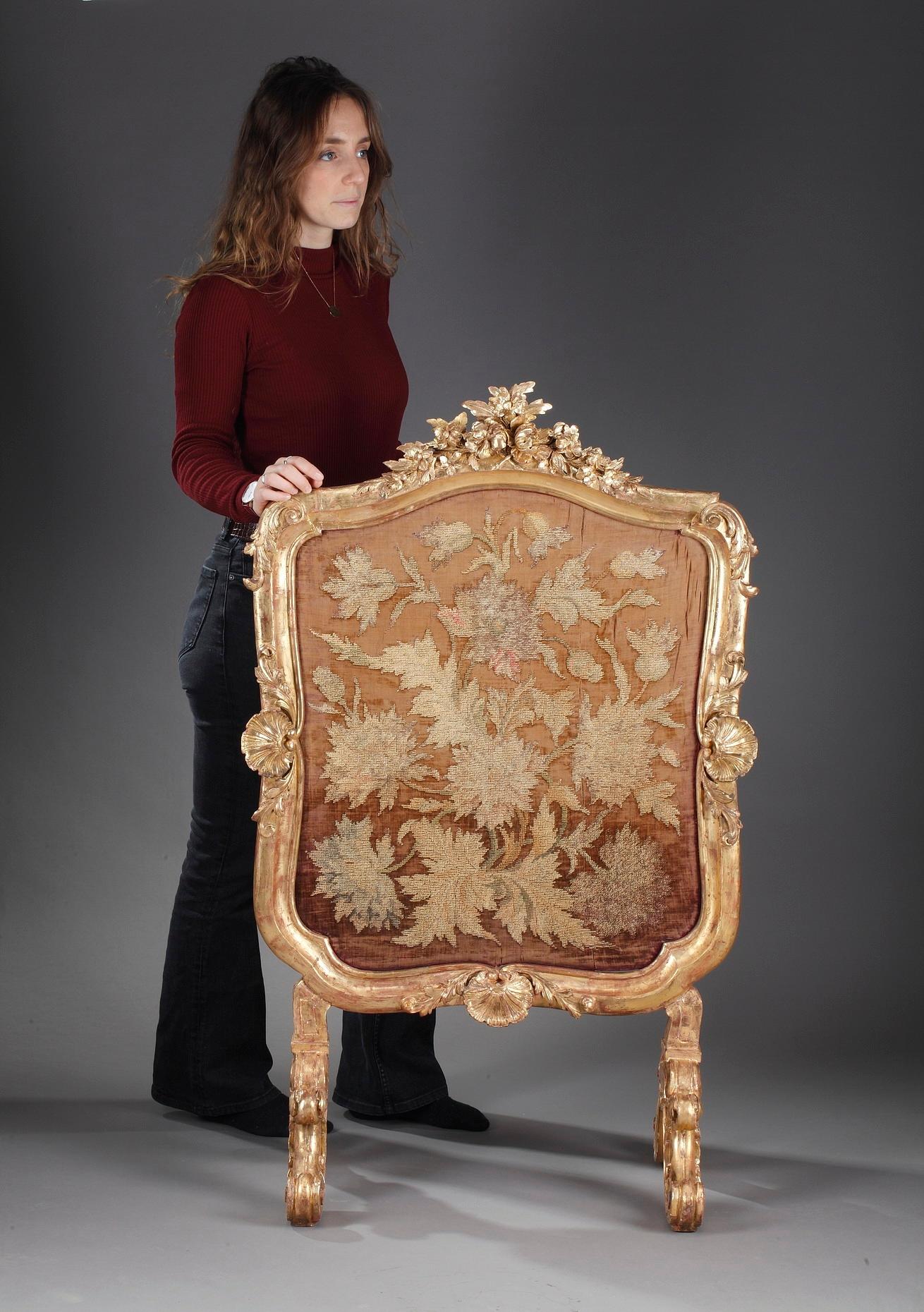 Louis XV Revival giltwood firescreen, intricately carved with Rocaille symmetrical and foliate decoration. Acanthus with floral and shell details surround the central part, designed to protect from the heat, crafted of silk fabric embellished with