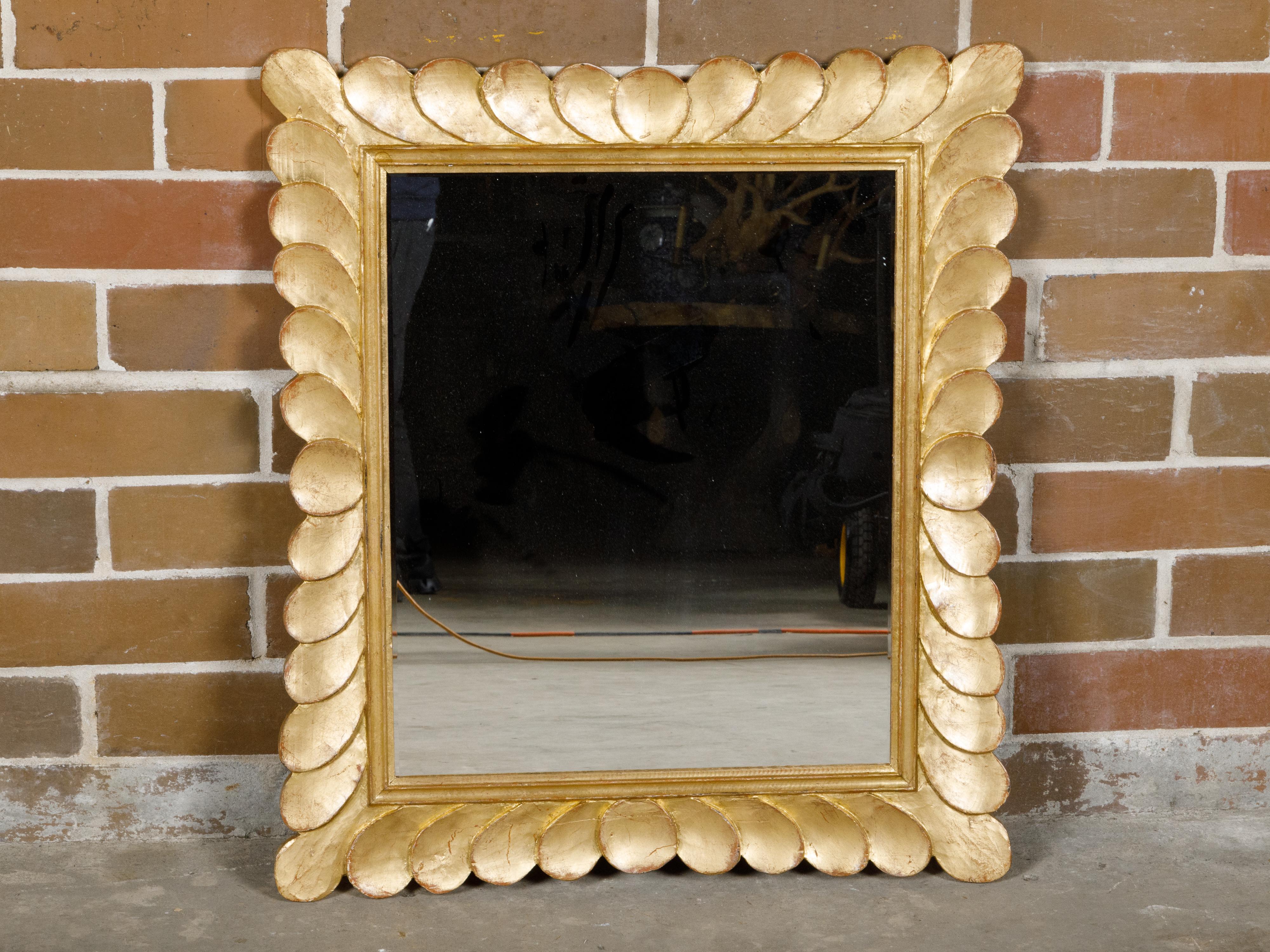 An Italian Midcentury giltwood mirror from circa 1950 with petal-themed frame. Step into the luxurious world of Italian Midcentury design with this circa 1950 giltwood mirror, a piece that exudes elegance and artistic flair. This mirror, with its