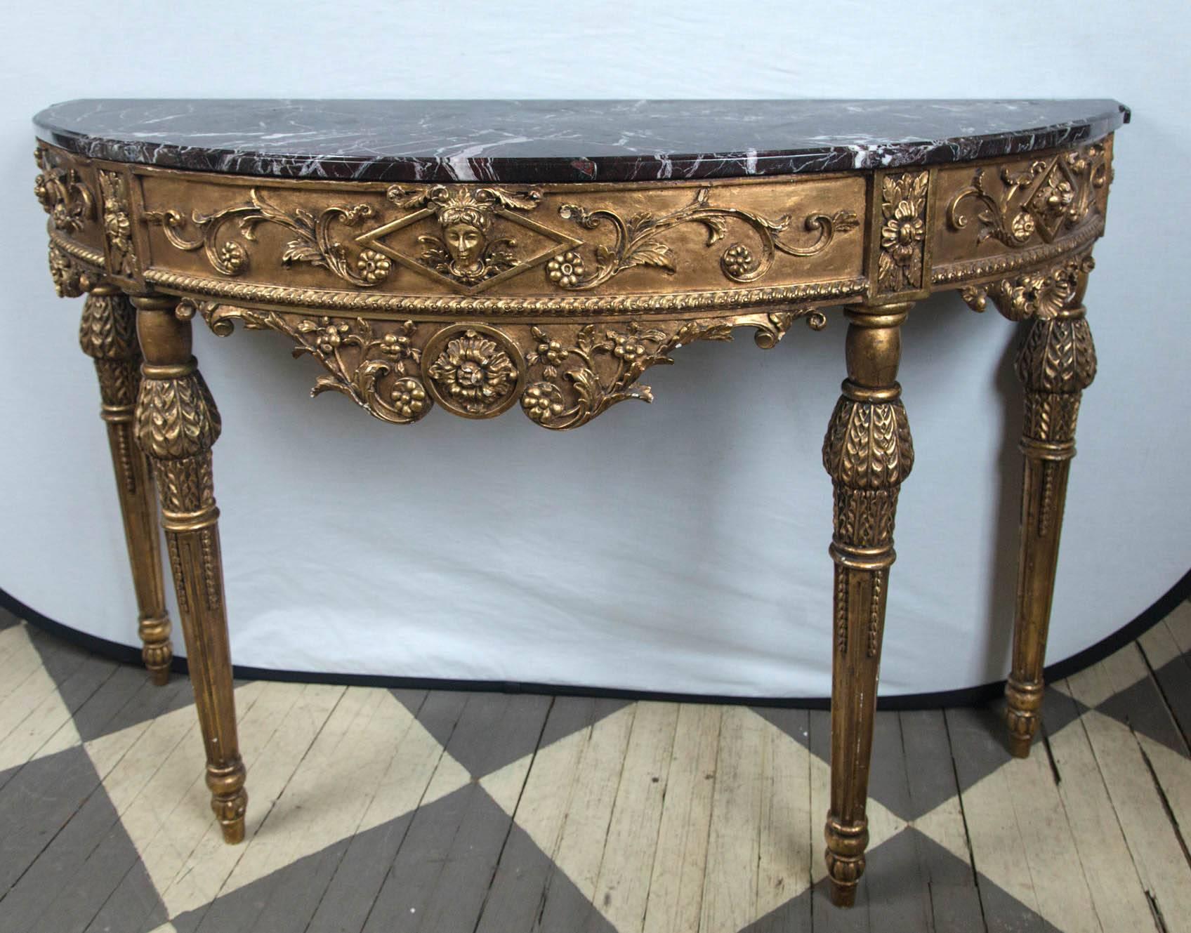Neoclassical style console, on four legs. The apron is centered by a female head, and fully decorated around with swags and flowers, Lower decorated aprons. Dark red and white marble. Gesso and gilt decoration.