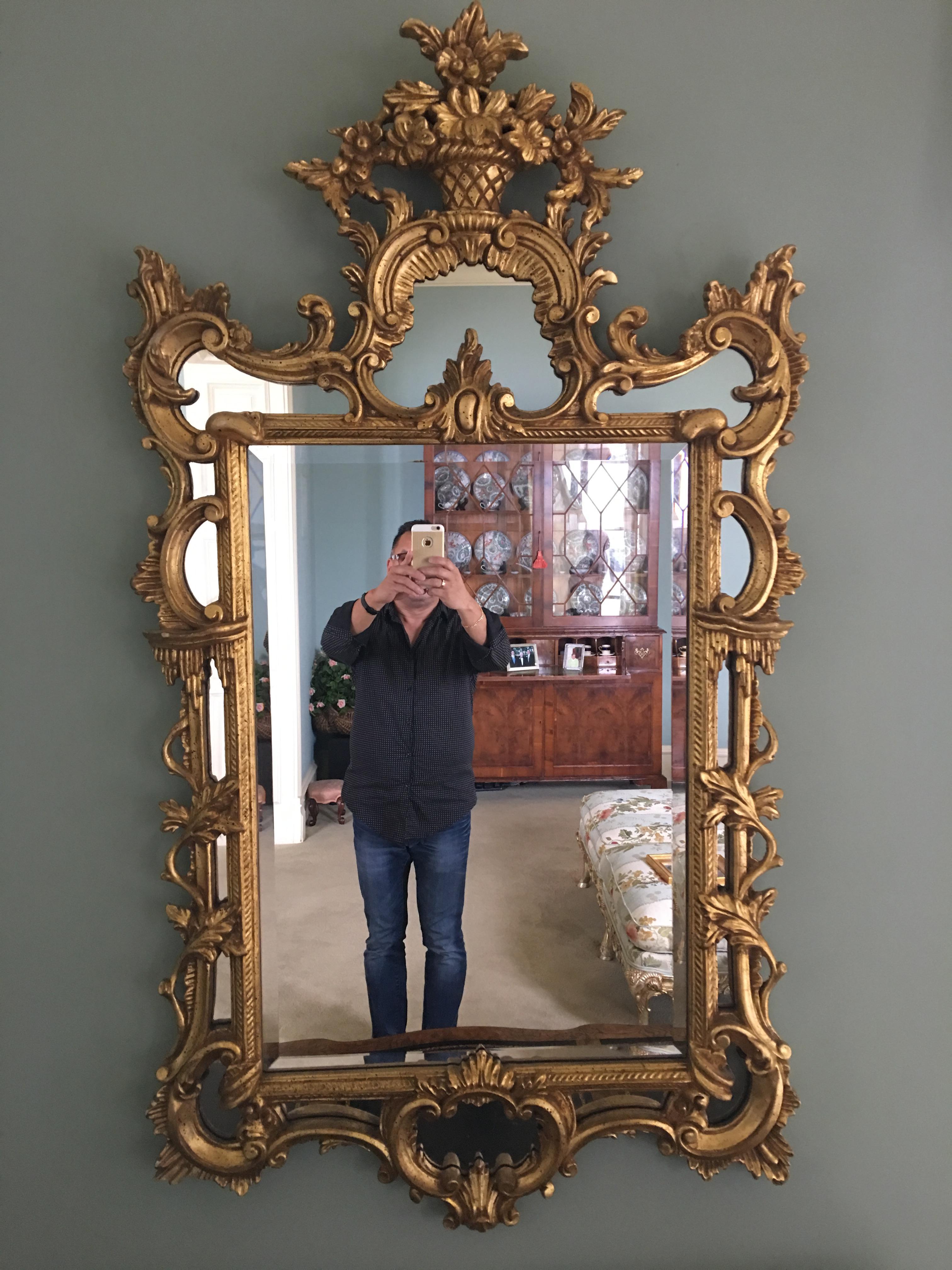 Giltwood mirror with a decorative floral basket at top, 20th century.