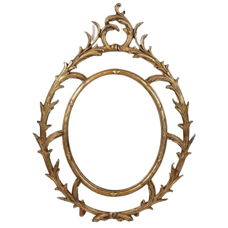 20ième siècle Miroir ovale en bois doré avec motif de volutes en vente