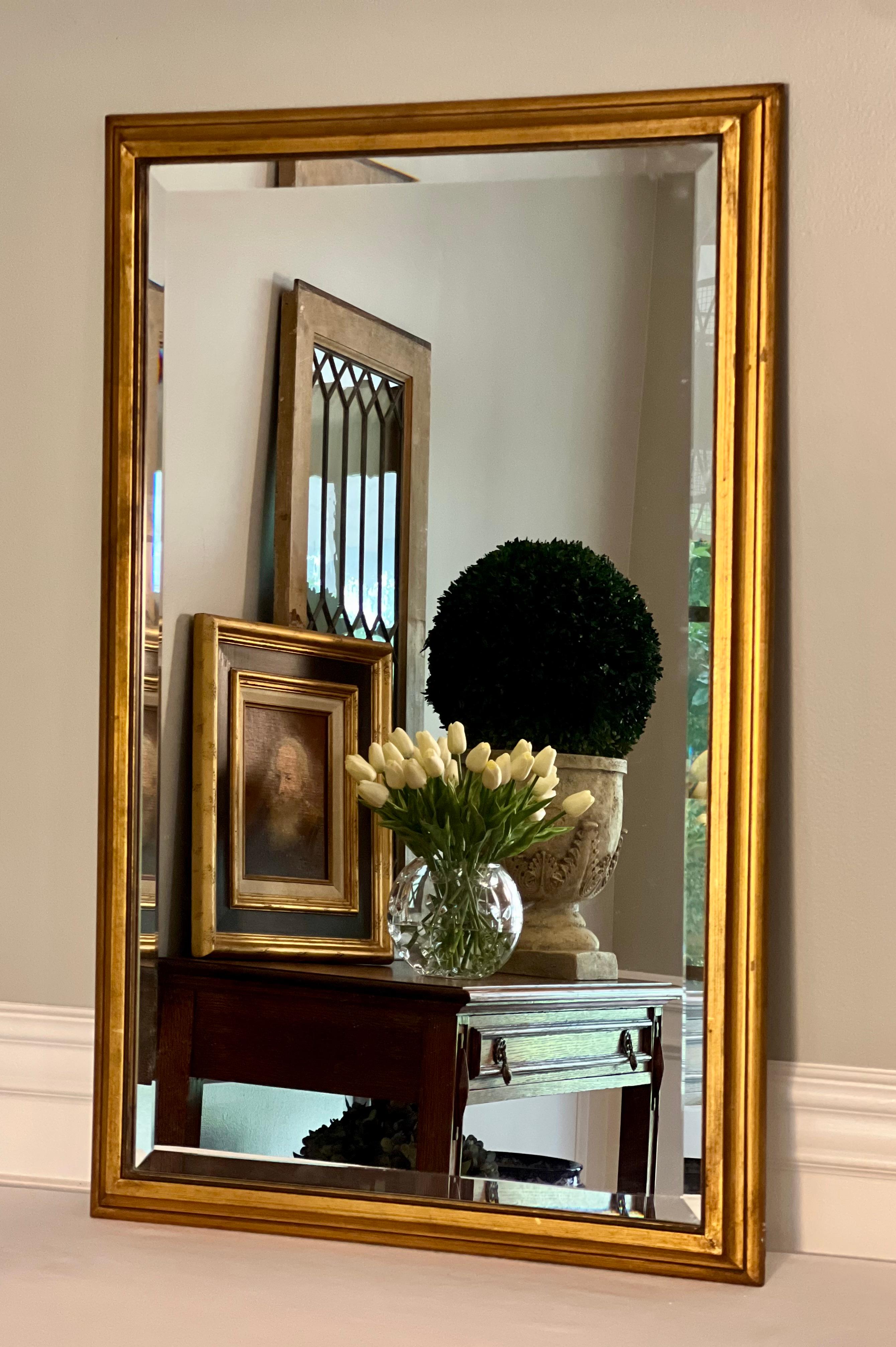 Classically styled rectangular beveled mirror with a carved giltwood frame, 1940s. Sturdy hardware is attached to the wood backing with the option to hang either vertically or horizontally. Currently has wire in place for portrait/vertical