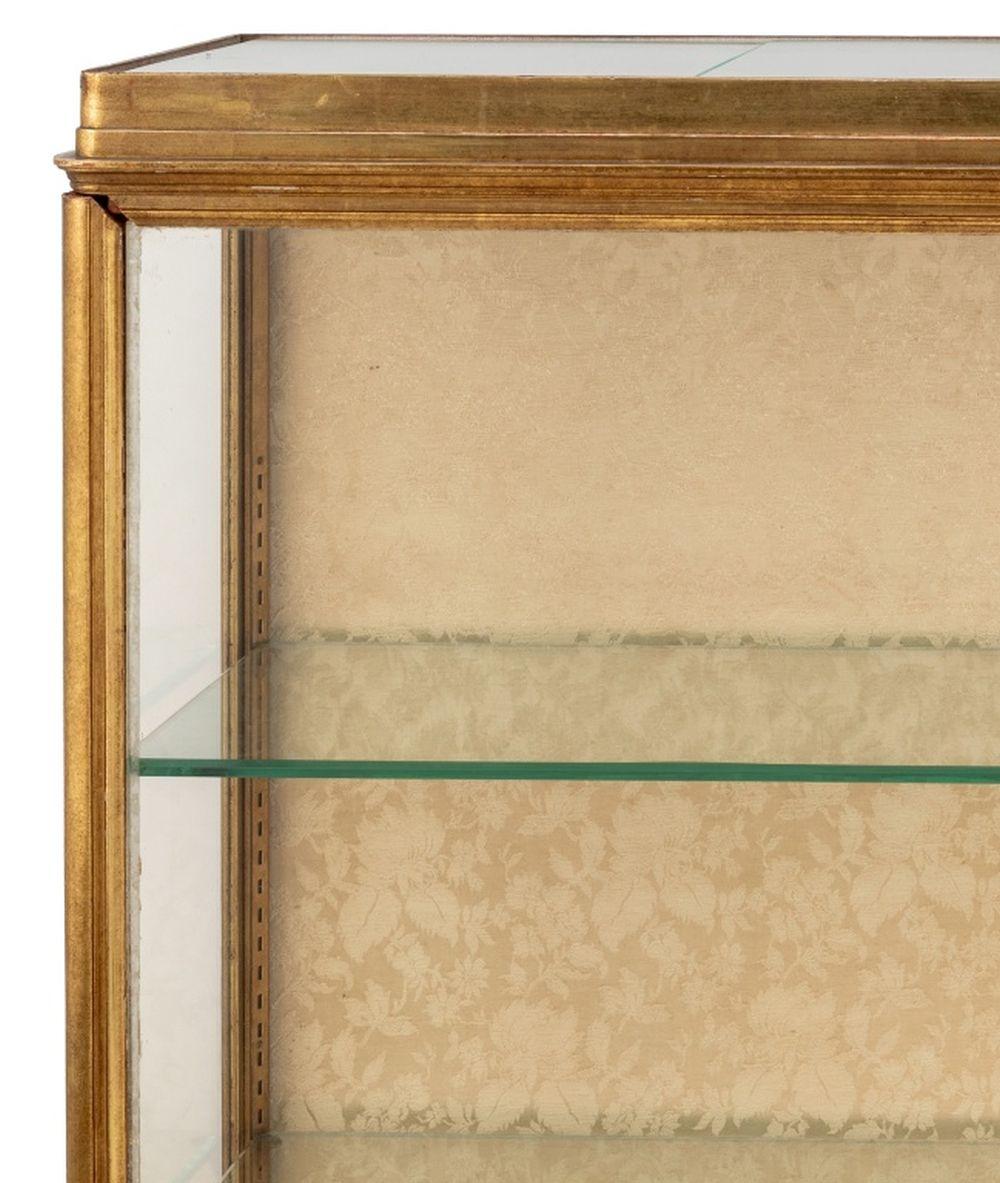 Rechteckige Vitrine aus Giltwood, frühes 20. Jahrhundert, mit einer Tür an einem Ende, die drei verstellbare Glasböden einschließt, auf einem geformten abgestuften Sockel, mit Innenbeleuchtung. 59,5