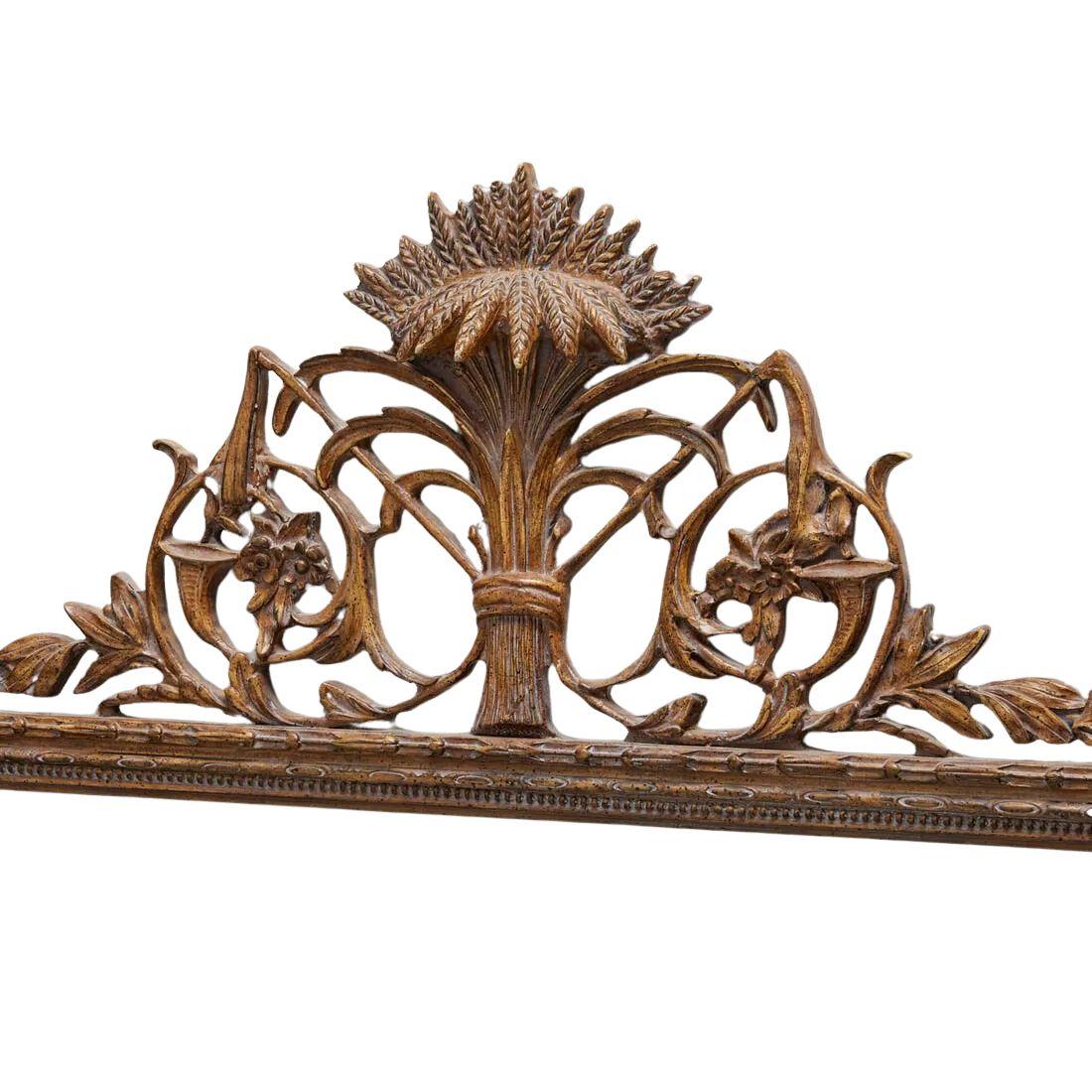 A giltwood rectangular mirror with a wheat and foliate motif crest.  The beveled mirror sits in a beautifully carved giltwood frame with bead detail, corner square rosettes. trailing leaves and topped with a sheaf of wheat at the crest flanked with