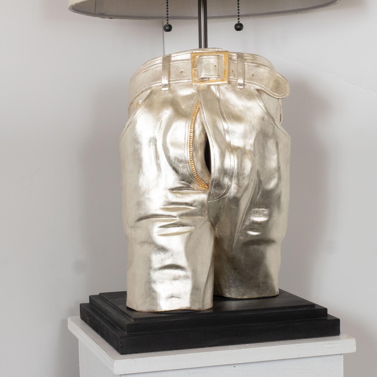 Single woodcarving table lamp with white gold finish depicting a pair of jeans in exquisite detail by master woodworker Carlos Villegas.
