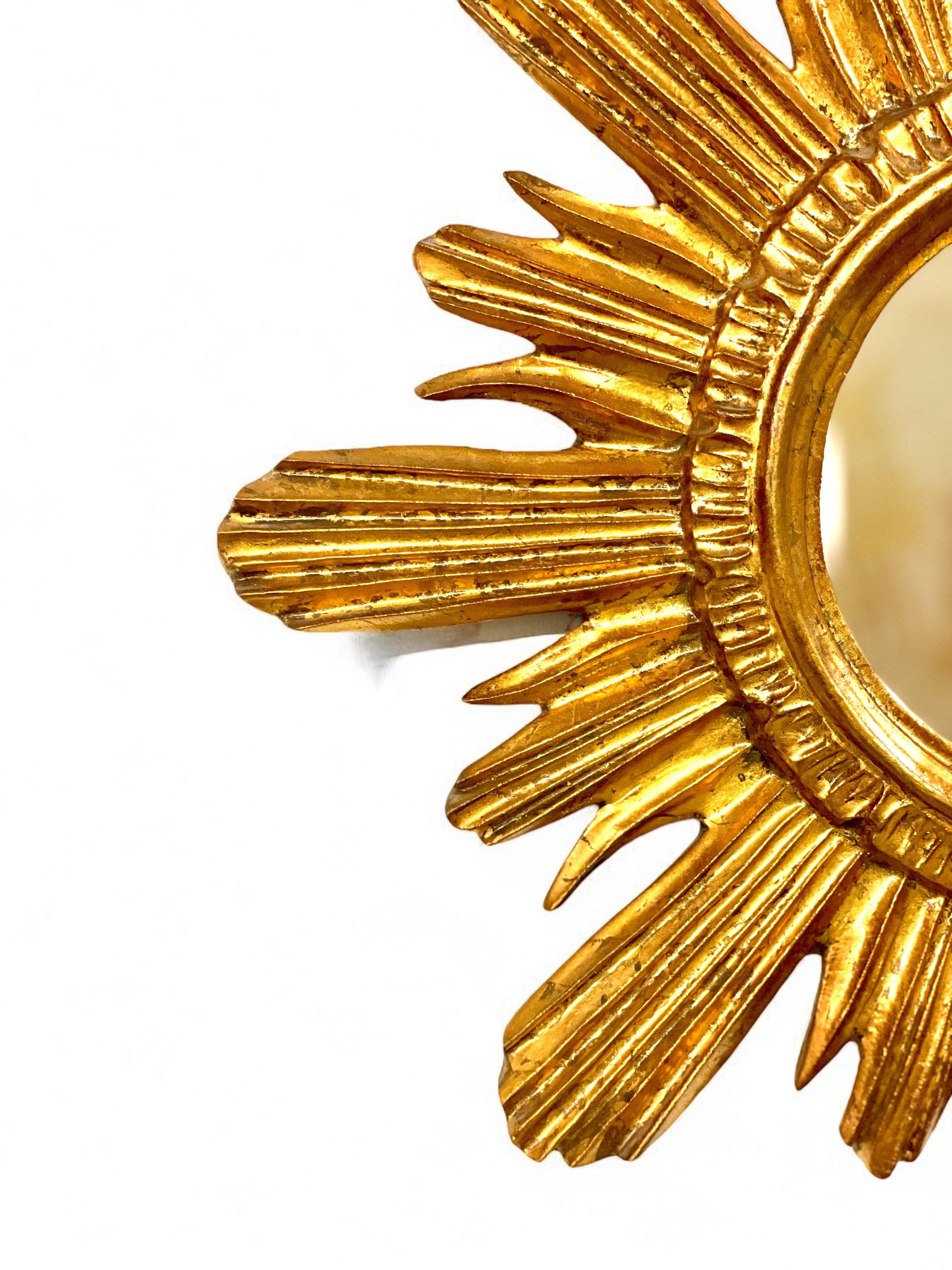 This elegant sunburst mirror is a remarkable piece of craftsmanship and timeless design. Measuring 44.5 cm in diameter, its carved wooden frame showcases a radiant gilt finish, reminiscent of the warm golden rays of the sun. The hand-carved rays