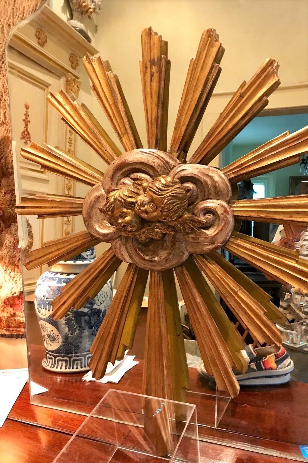 An intricately assembled carved Giltwood sunburst. The center affixed with silver leaf clouds and two cherubs ( or Angels) in relief. Bleeding of red bole throughout. Sturdy

Minor age/ shrinkage cracks. Rubbing and oxidation to the gilt finishes.