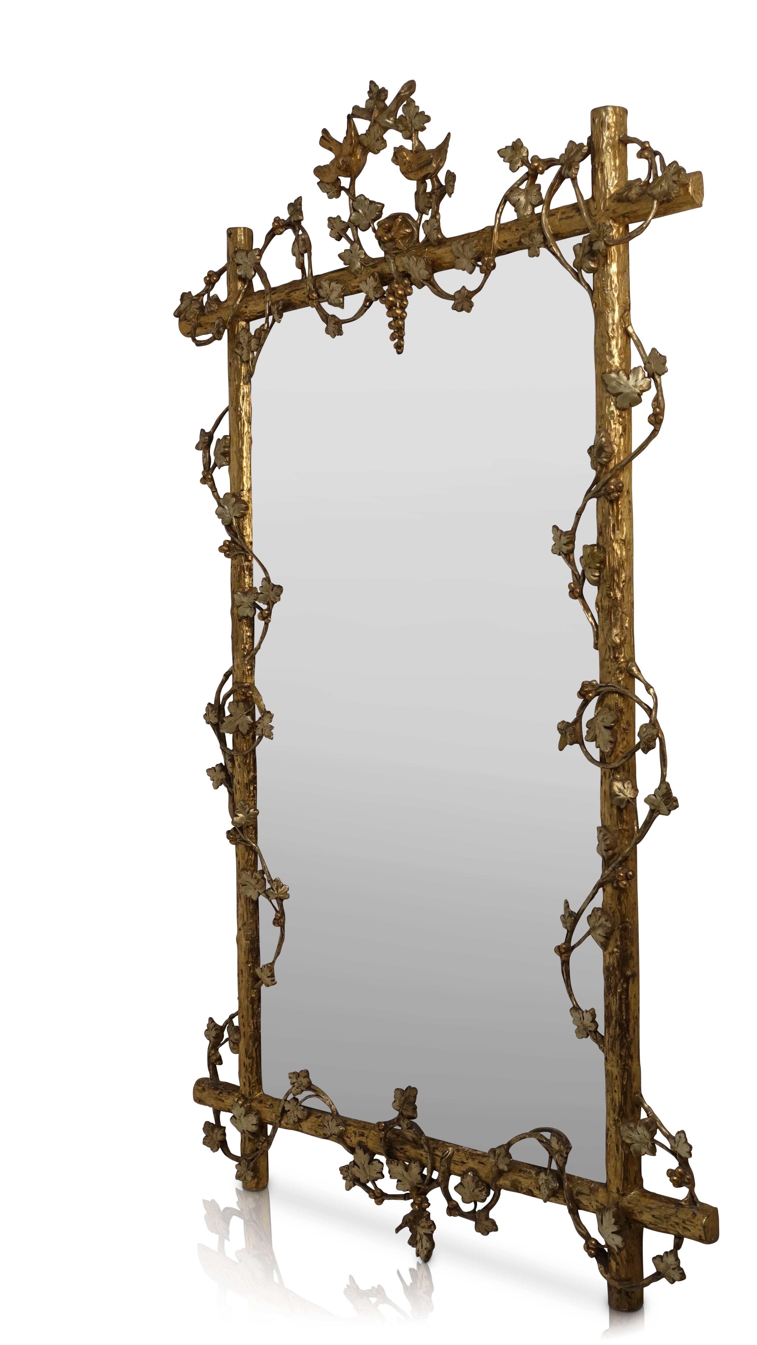 An impressive two tone gold gilt hand carved tree branch mirror with bevelled glass. Vining grape leaves and grapes wrapping around the frame, and having two birds above a hanging grape cluster at the top. Retains its original old mirror, American,