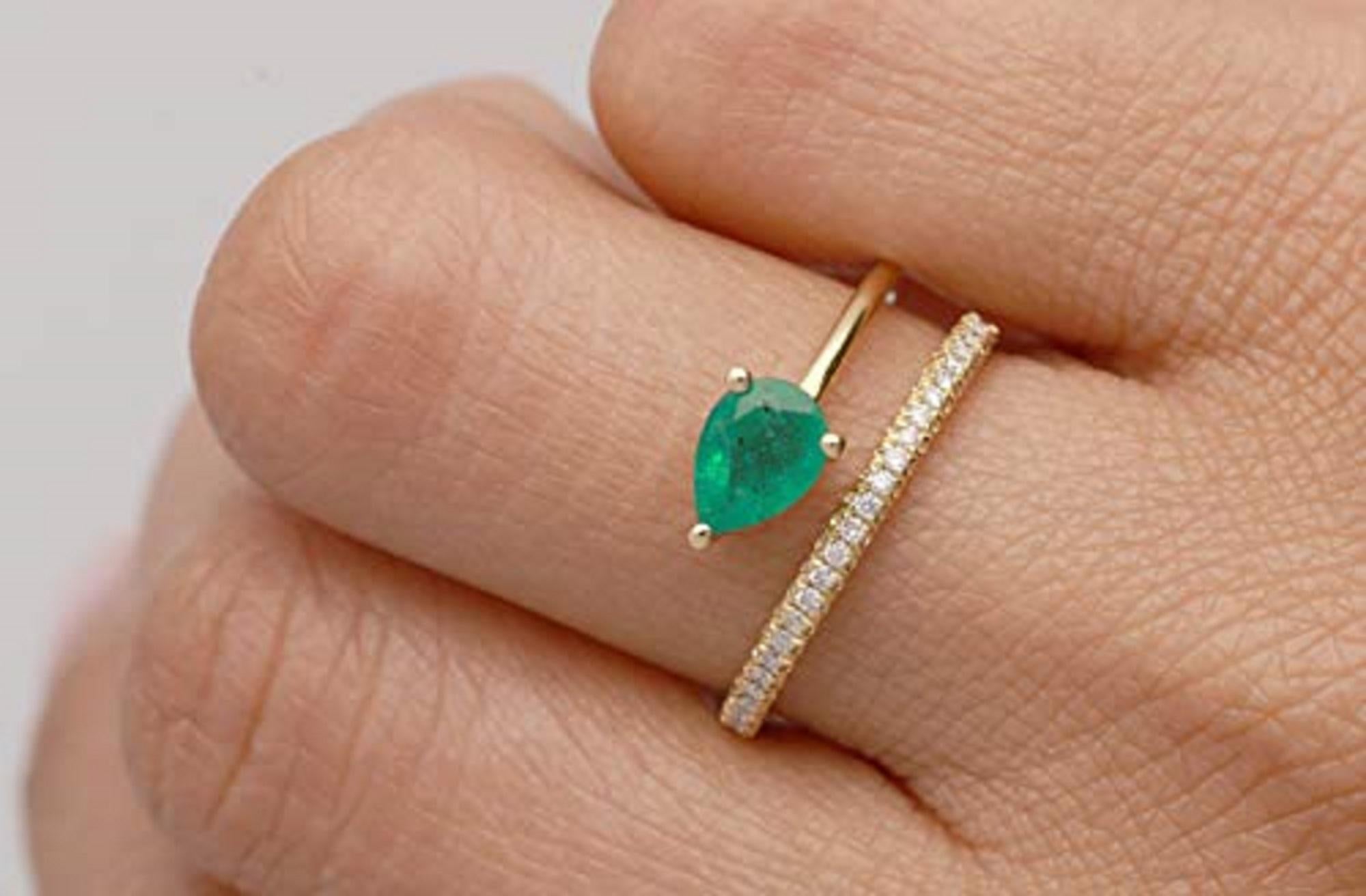 A stunning green emerald is balanced perfectly in the center of this ring, with the glossy band moving above and below. The jewelry has sparkling white diamonds along one side and the 18k yellow gold offers the ideal color contrast to such an