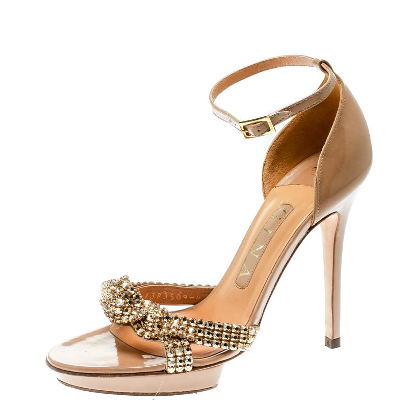 Channel your inner goddess with these stunning sandals from Gina that will make you look divine! These beige sandals are crafted from patent leather and feature an open toe silhouette. They flaunt a single vamp strap that is exquisitely embellished