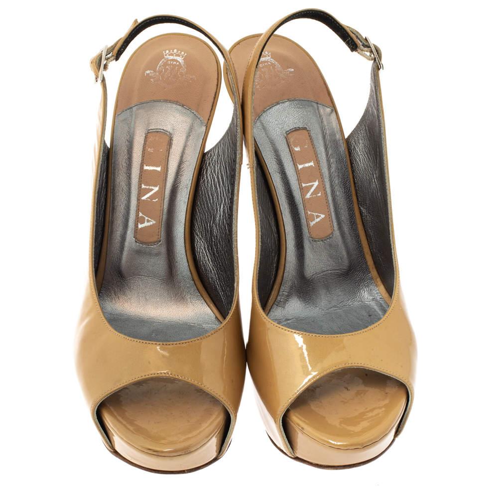 These classic sandals by Gina are closet must-haves. They come in a neutral tone of beige and are crafted from glossy patent leather. They are styled with peep toes, platforms, slingbacks, gold-tone hardware and 13 cm heels. They are finished ith