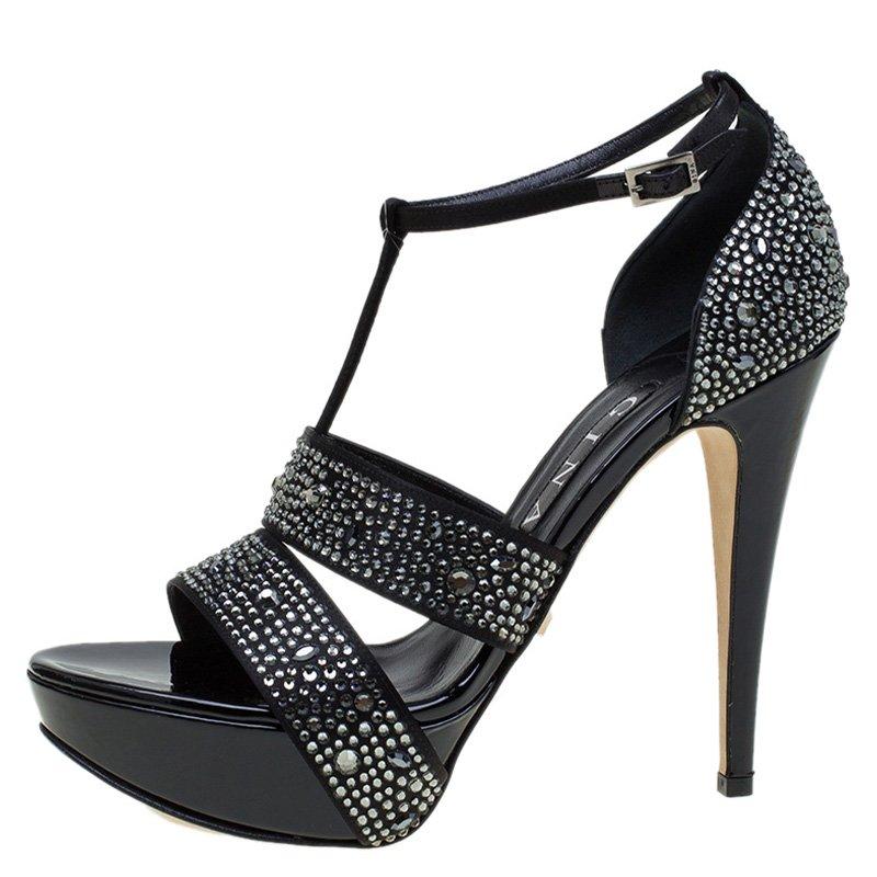 Gina's elegantly styled sandals are set on a platform sole with sleek pencil heel. Featuring stunning embellished straps, this black pair is finished with covered rear and a T-strap buckle closure. Wear yours for an evening event or wedding with a