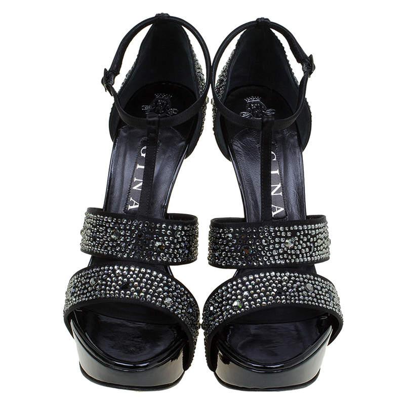 Gina's elegantly styled sandals are set on a platform sole with sleek pencil heel. Featuring stunning embellished straps, this black pair is finished with covered rear and a T-strap buckle closure. Wear yours for an evening event or wedding with a